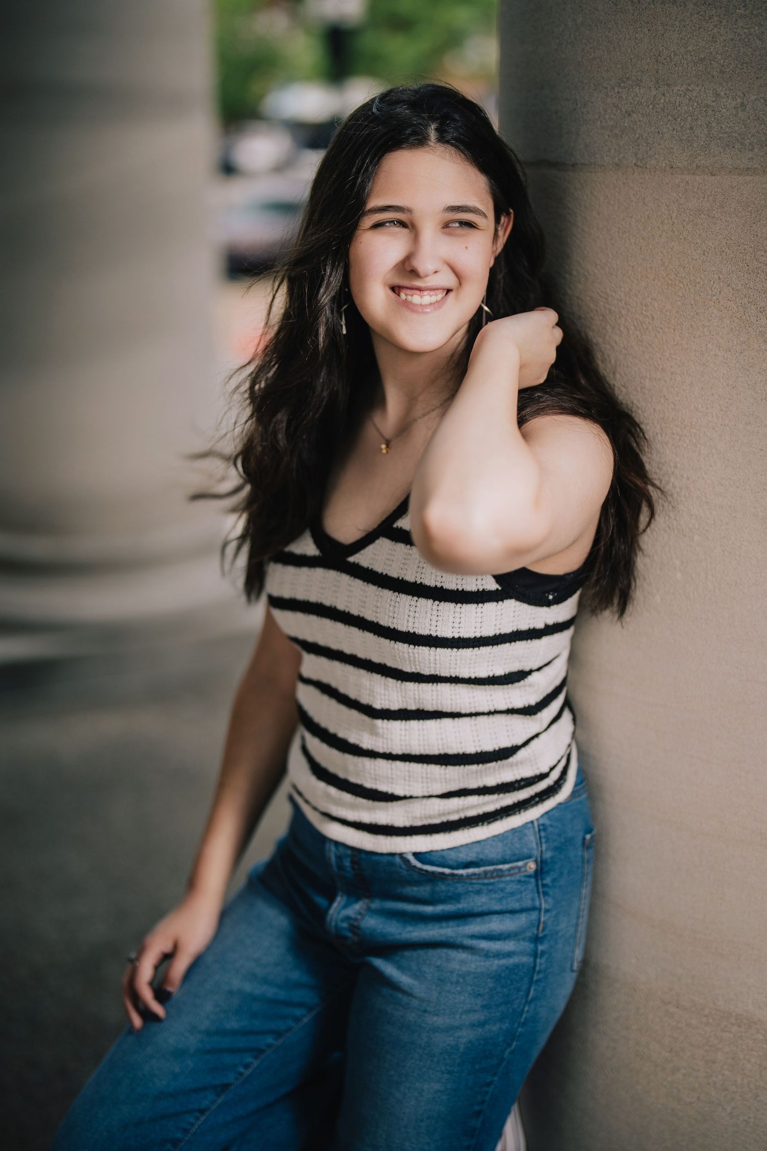 A casual portrait of someone in a striped top and jeans leaning against a wall outdoors. Murfreesboro, Tennessee.