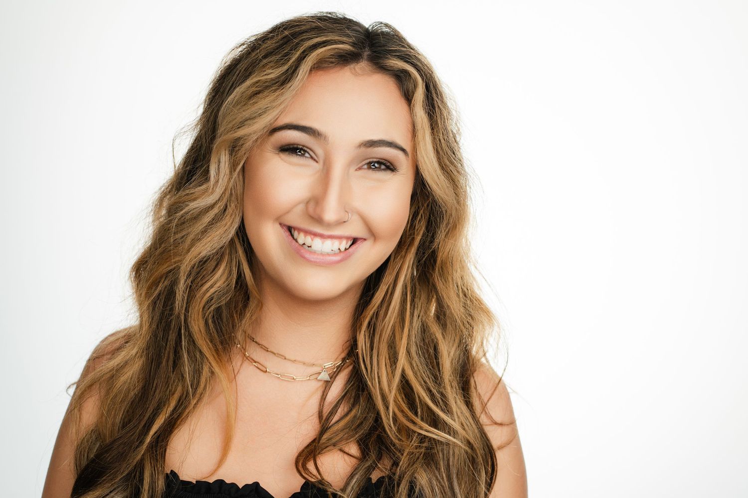 Portrait of woman with long wavy hair wearing black top against white background. Nashville, Tennessee.