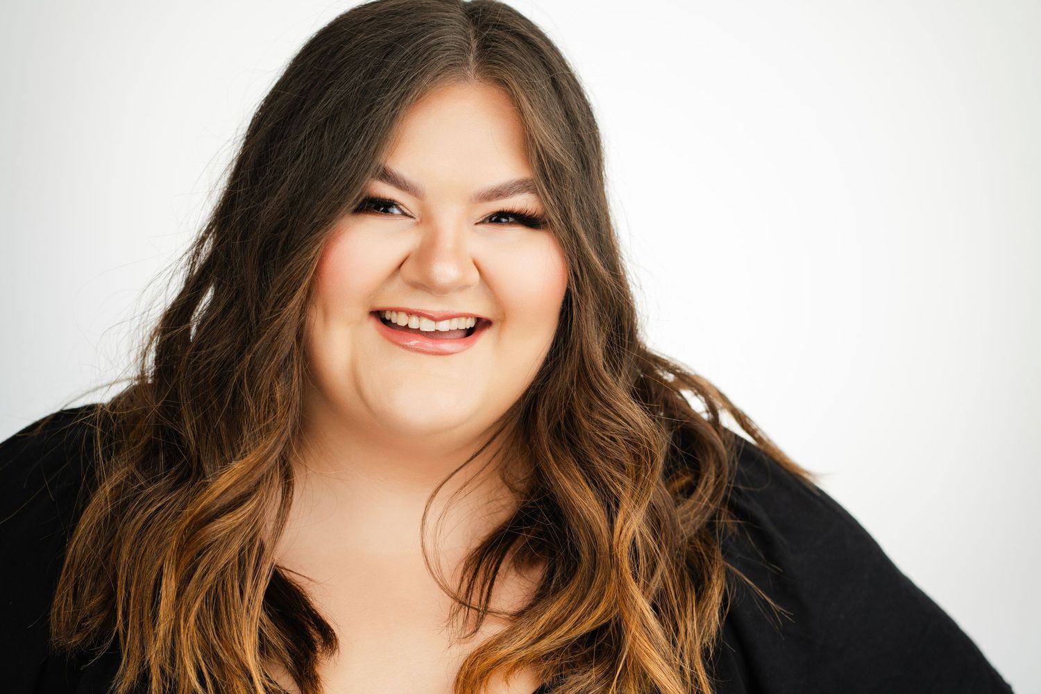 Woman with long brown hair laughing joyfully against white background. Nashville, Tennessee.