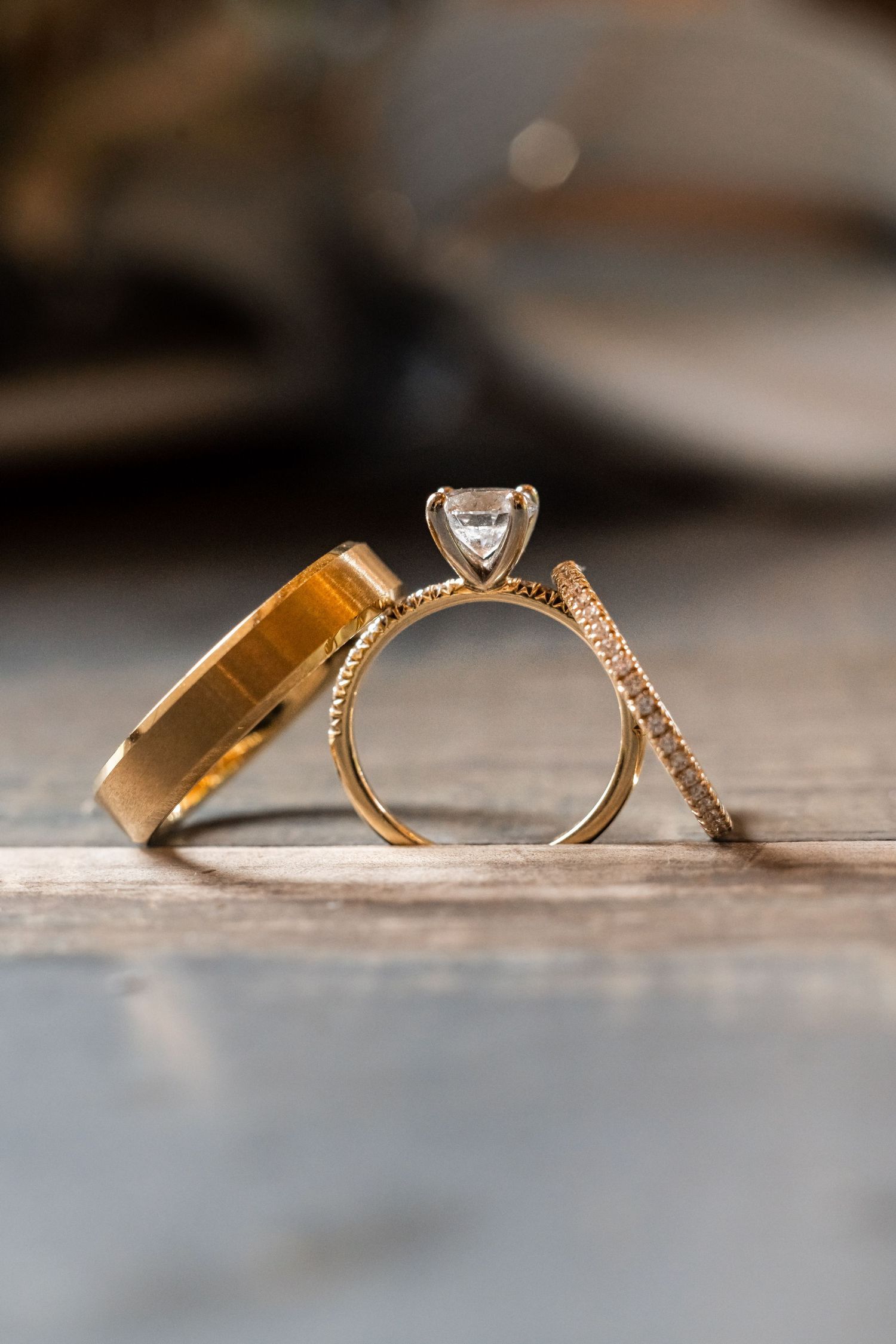 Close-up of elegant gold wedding rings and diamond engagement ring on wooden surface. Nashville, Tennessee.