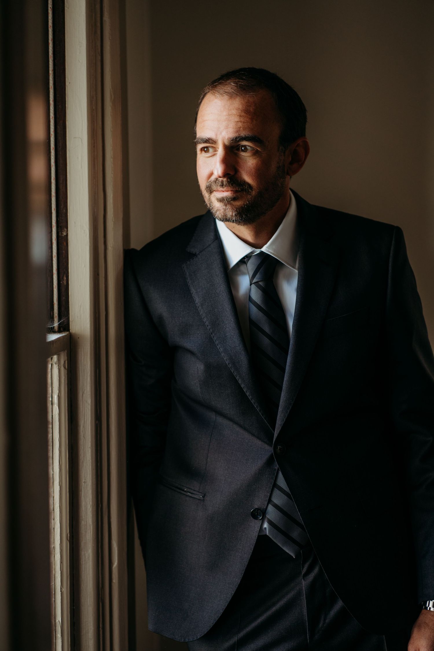Window light portrait of someone in formal attire against a neutral background. San Francisco, California.