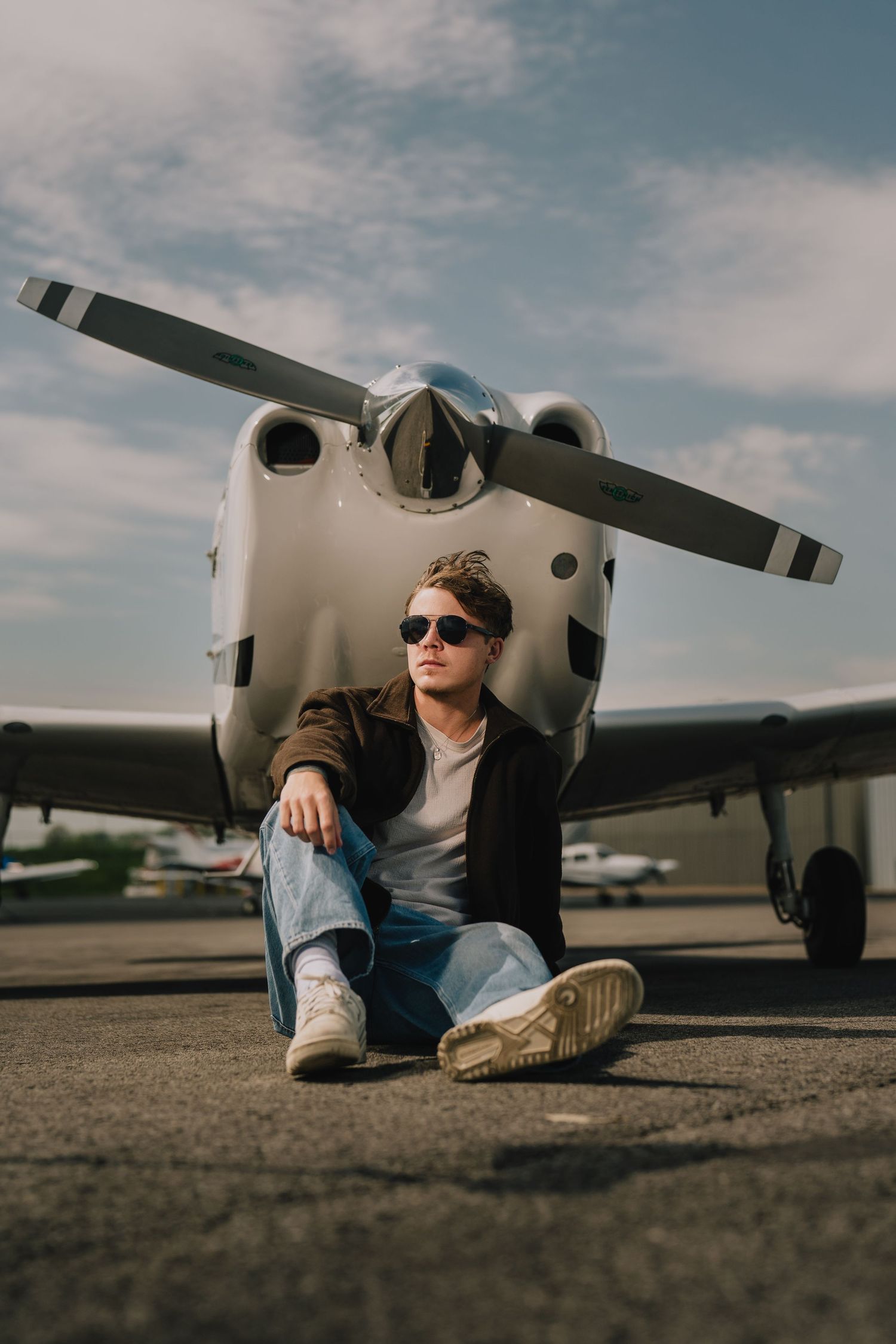 A casual portrait of someone sitting in front of a small aircraft wearing sunglasses and casual attire. Murfreesboro, Tennessee.