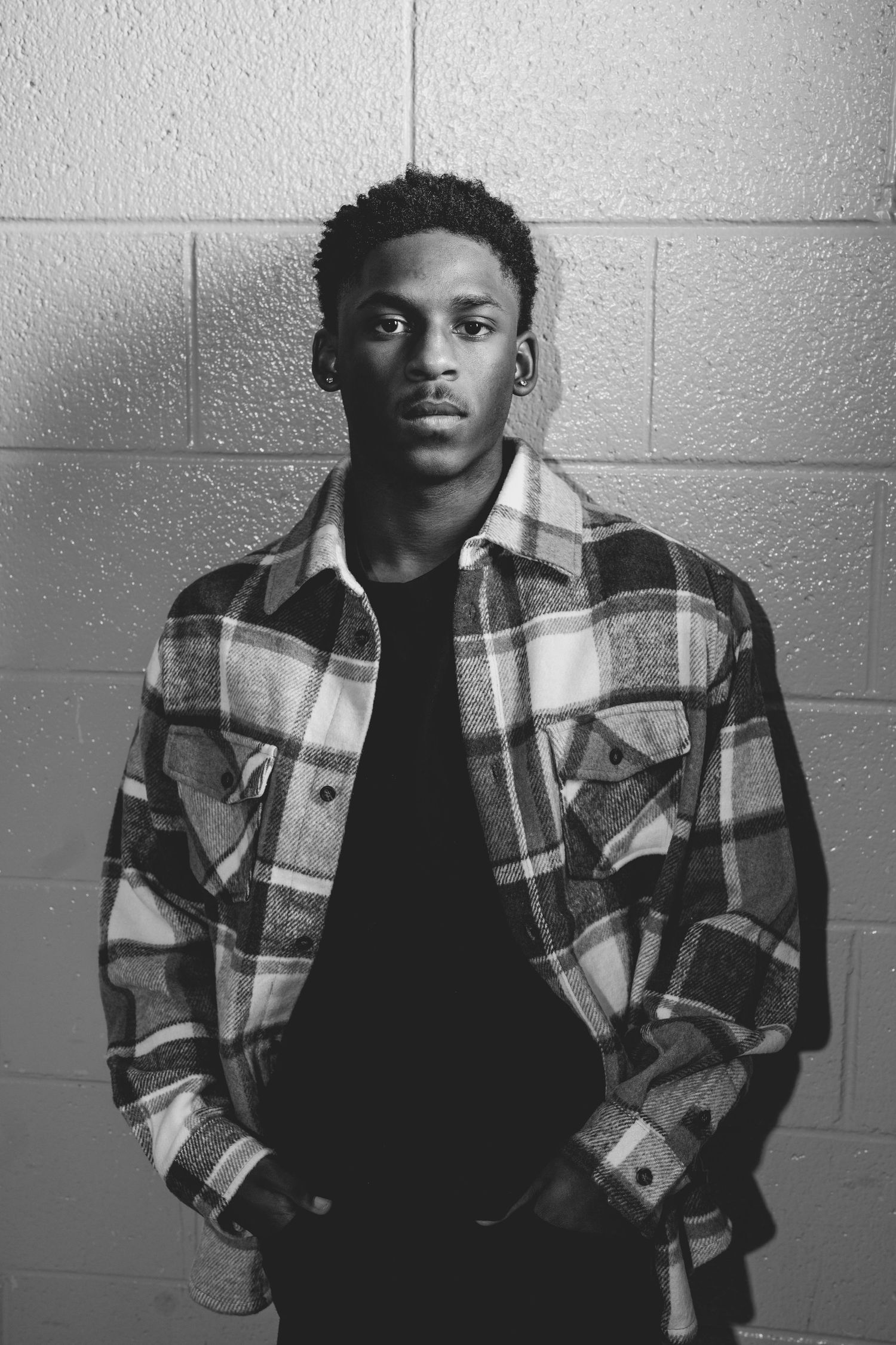 Classic black and white portrait against concrete wall wearing plaid flannel jacket. Nashville, Tennessee.