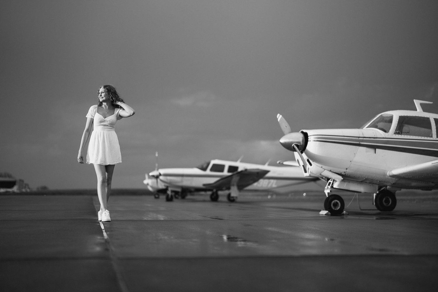 Black and white retro photograph of figure in dress near vintage aircraft on airfield. Nashville, Tennessee.