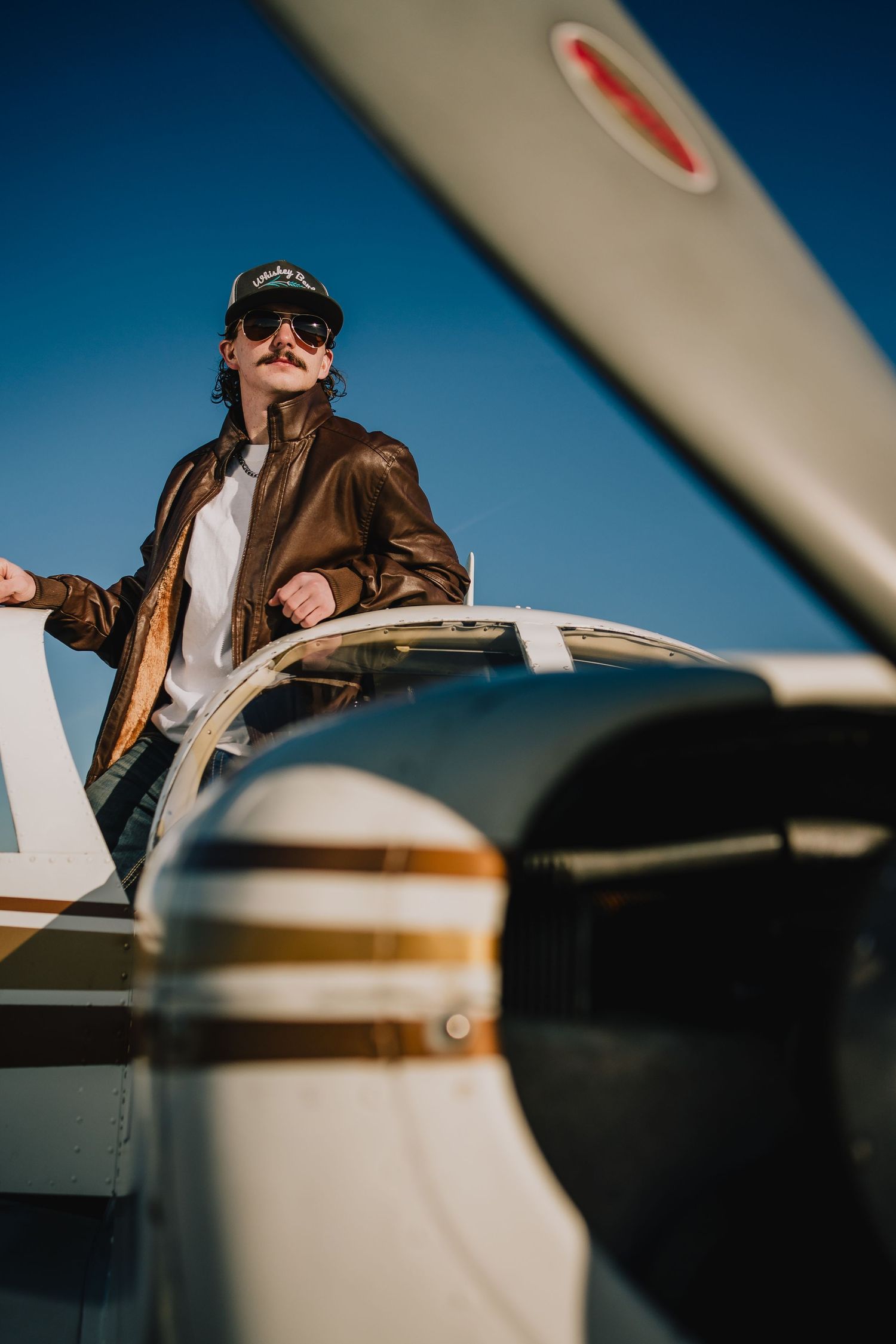 Low angle view of pilot in leather jacket standing in small aircraft cockpit. Nashville, Tennessee.
