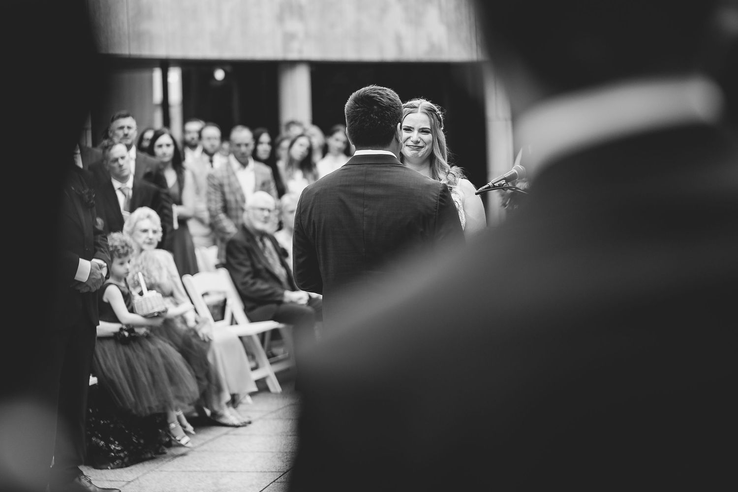 A black and white photo capturing a joyful ceremony moment with guests seated in the background. Milwaukee, Wisconsin.