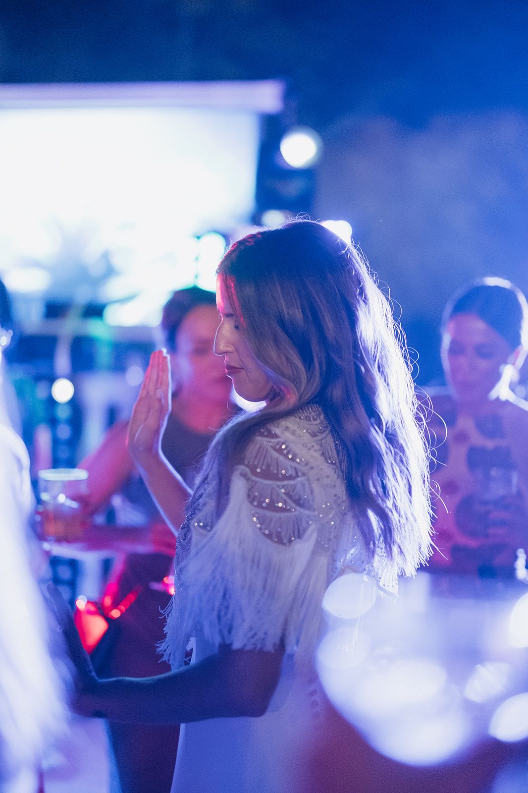 Elegant dancer in white lace twirling under blue atmospheric lighting.