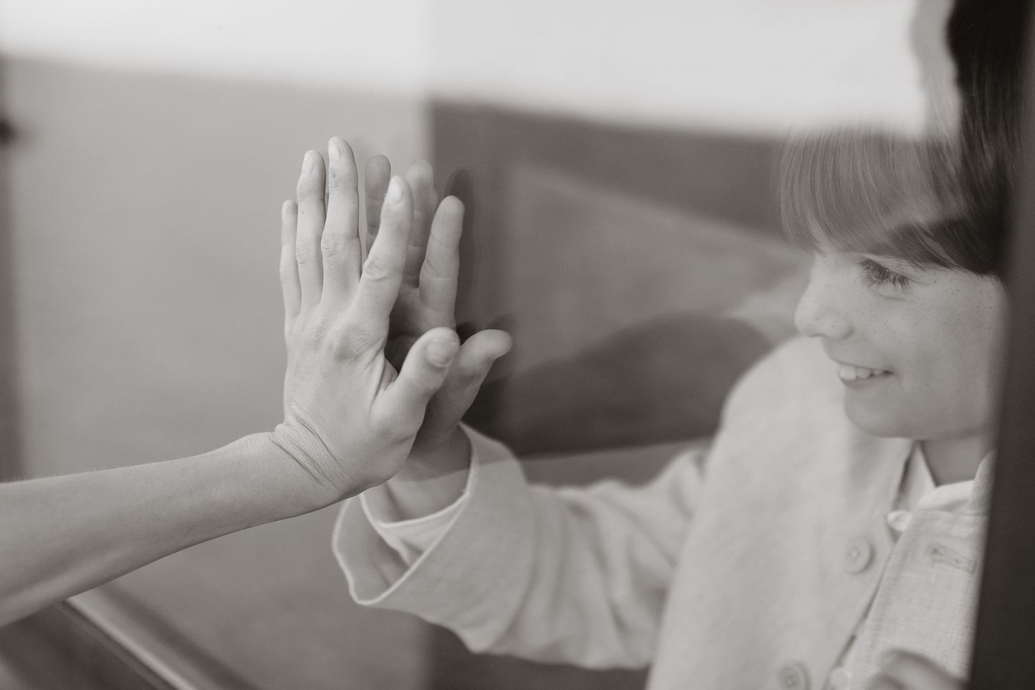 Two hands reaching out and touching palm to palm in a tender moment captured in black and white.