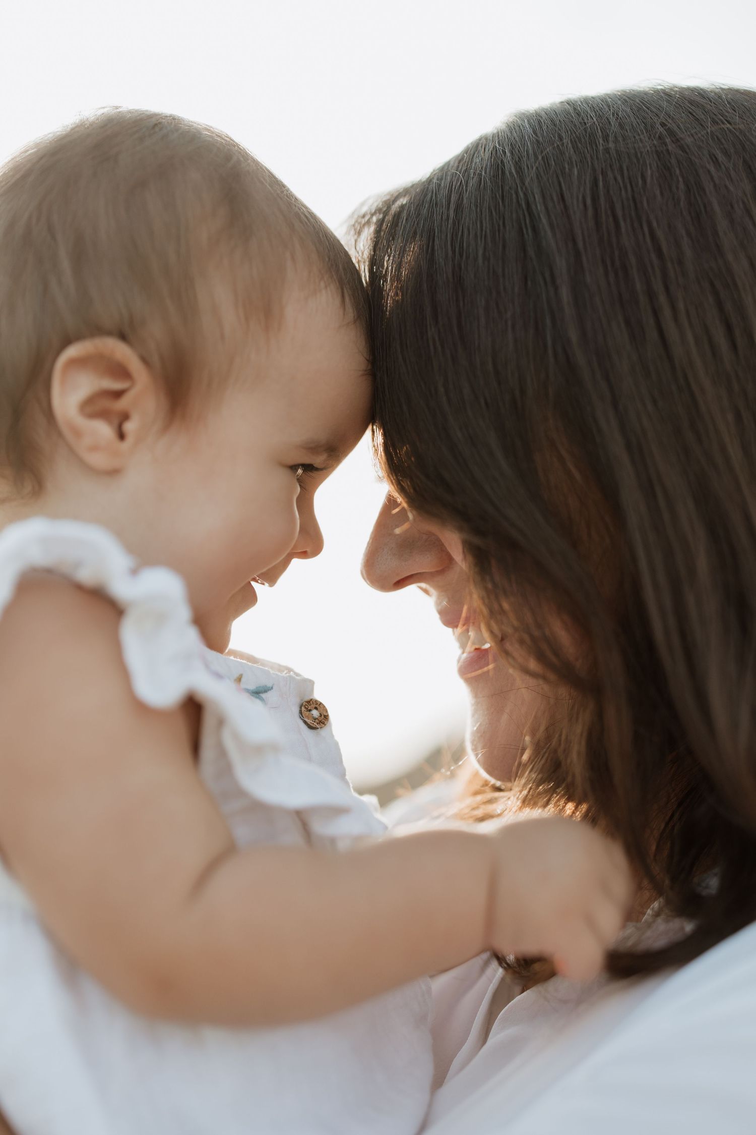 Sunlit portrait of baby and caregiver sharing genuine laughter together.