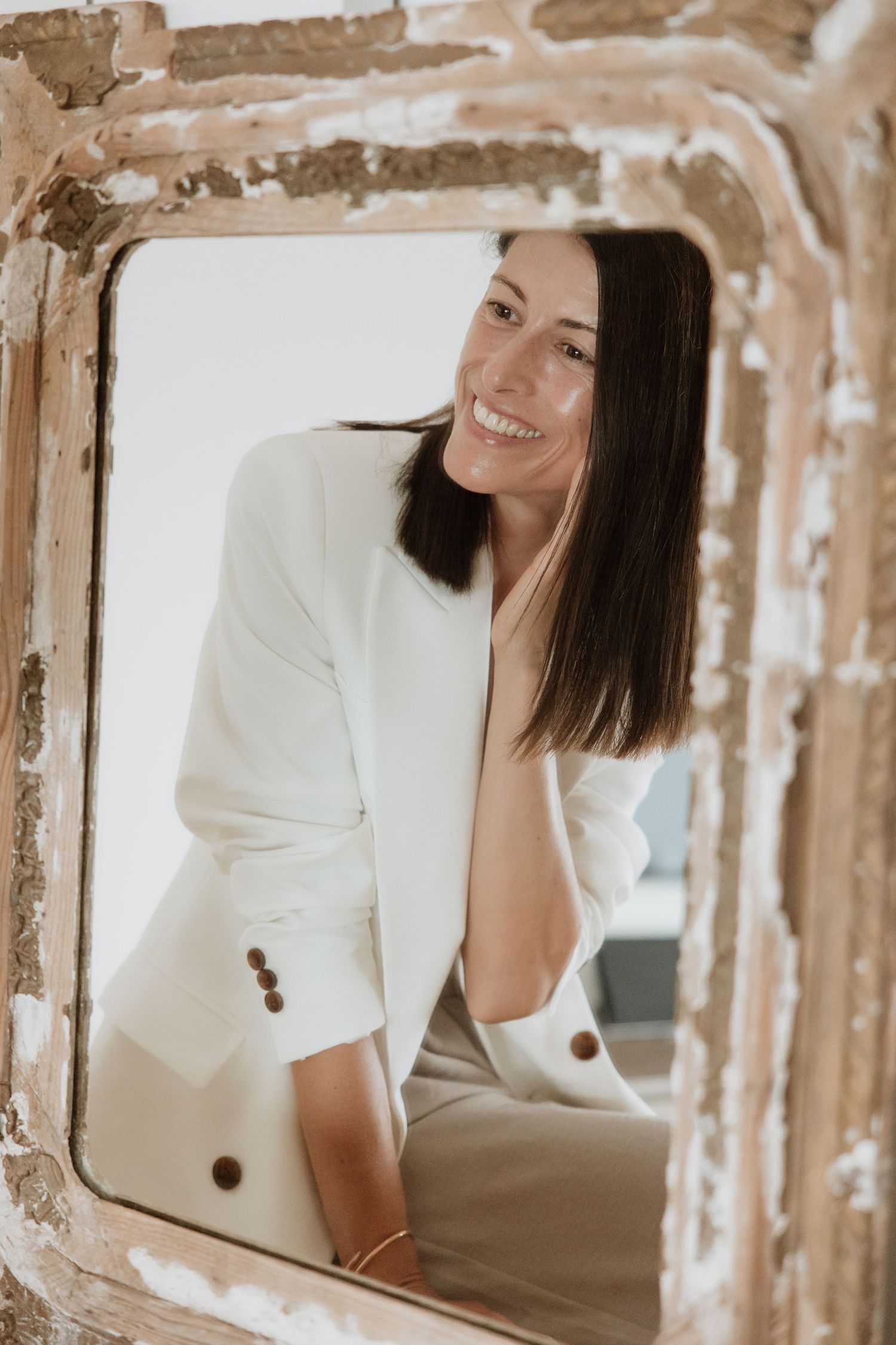 Creative portrait through vintage mirror frame with distressed paint texture.