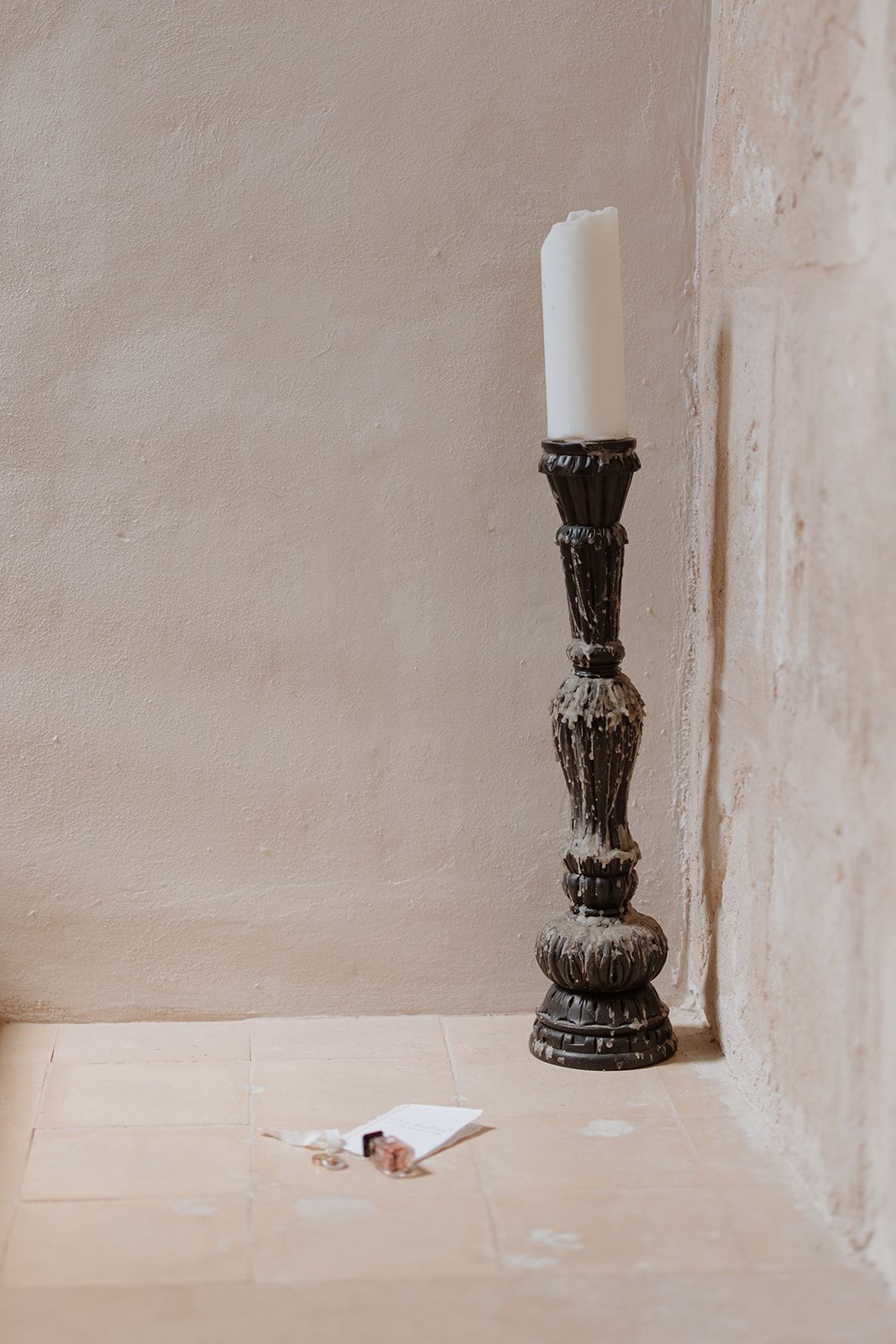 Decorative black pedestal stand photographed against beige wall.