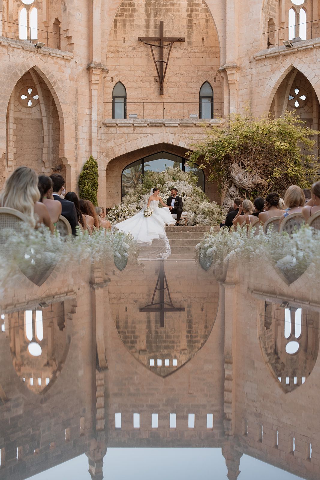 Cathedral ceremony with mirrored reflection of gothic architecture and floral decorations.