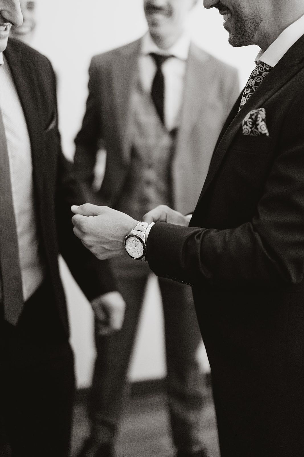 A close-up of hands adjusting formal wear details at a wedding.