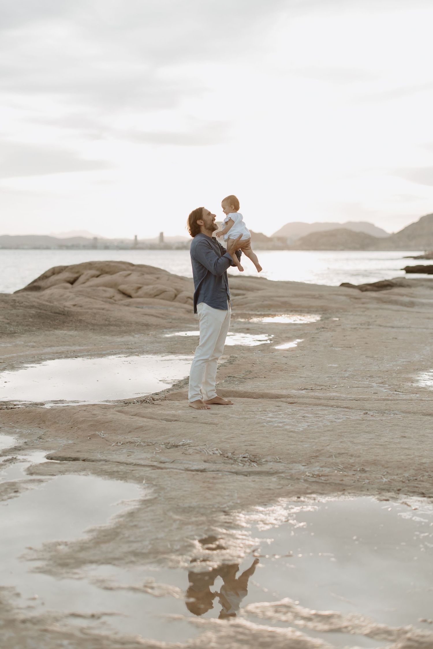 Family enjoying a peaceful moment on rocky coastal landscape at sunset.