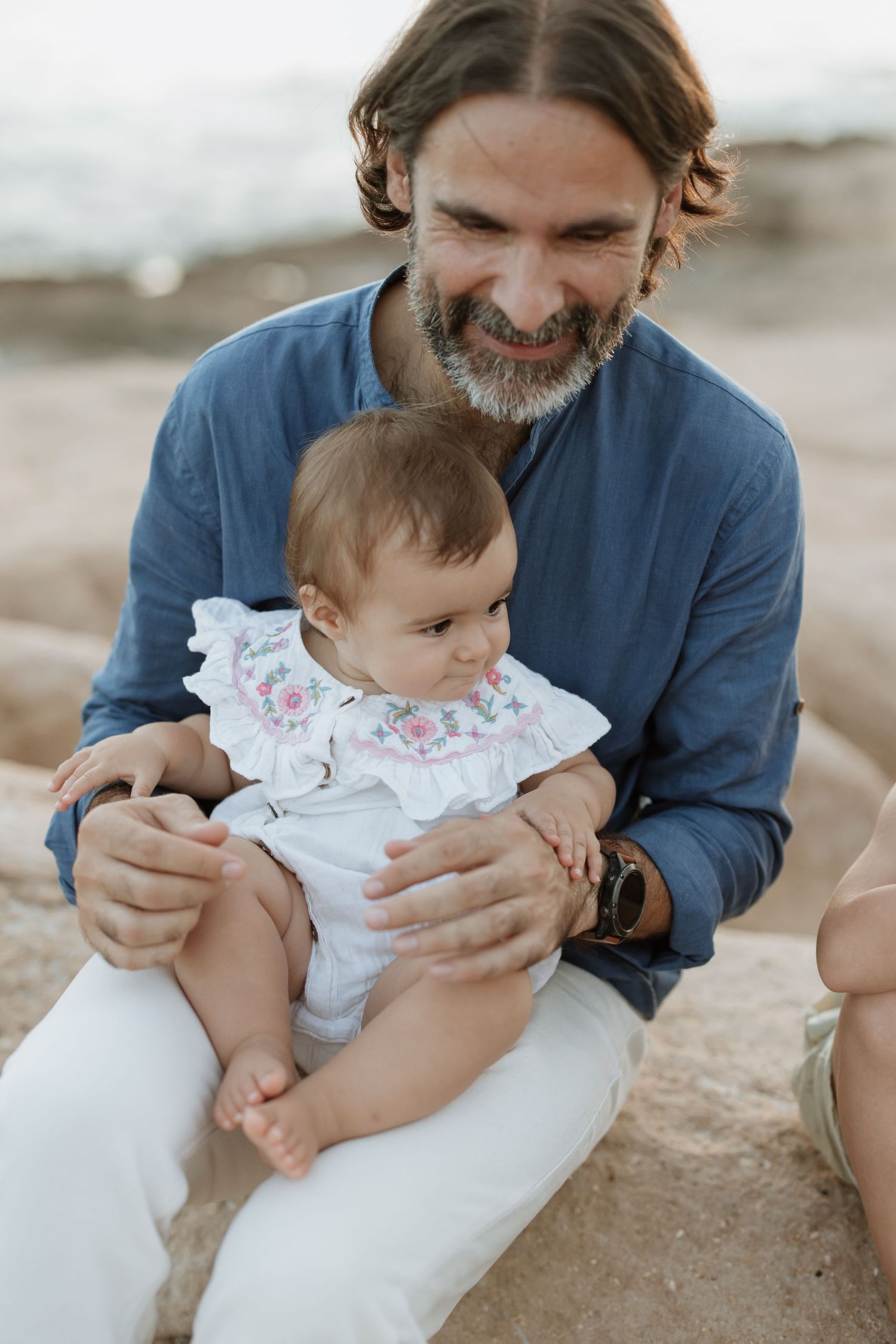 A tender moment shared between a parent in blue and an infant wearing white.