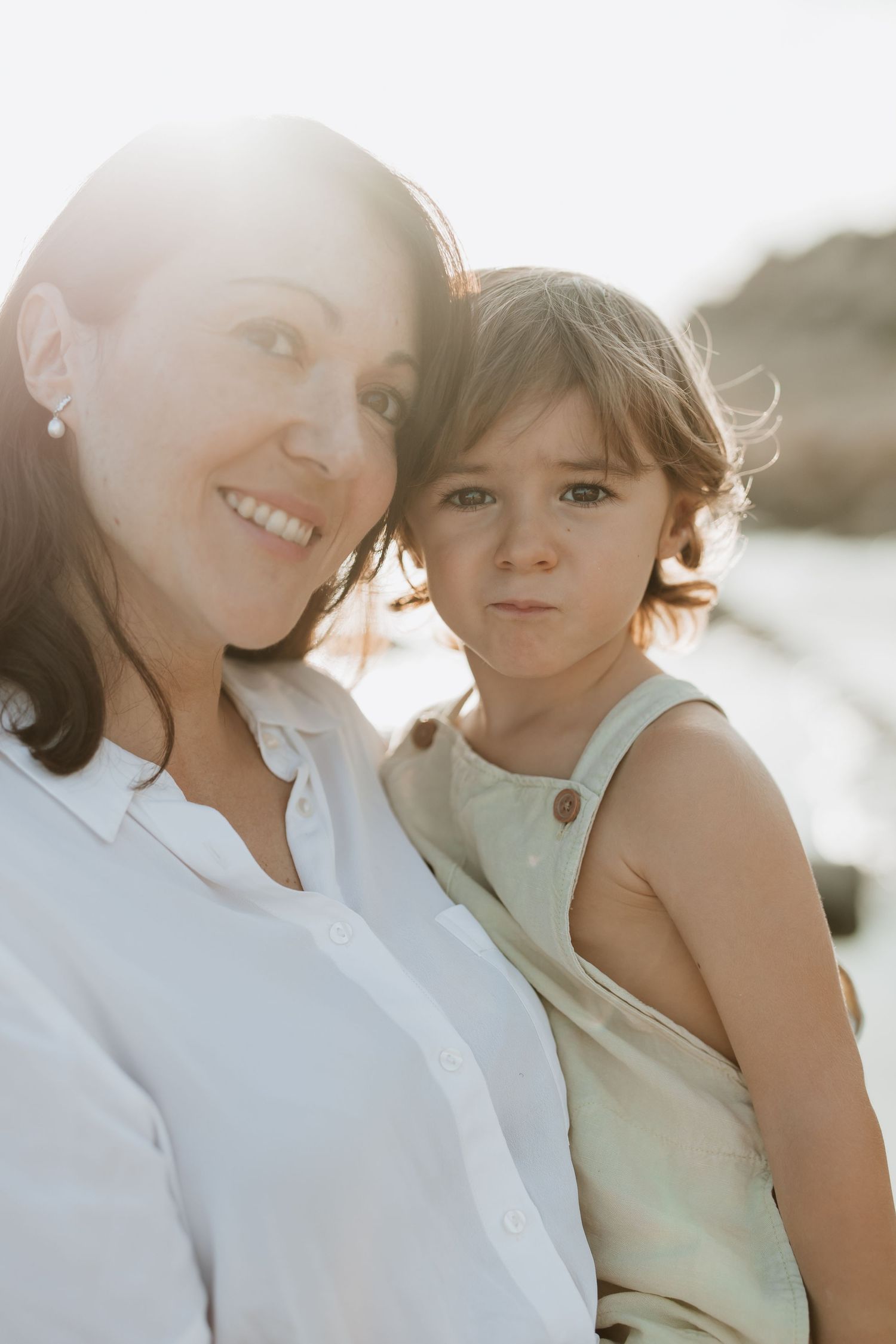A parent and child share a tender moment together at sunset by the ocean.