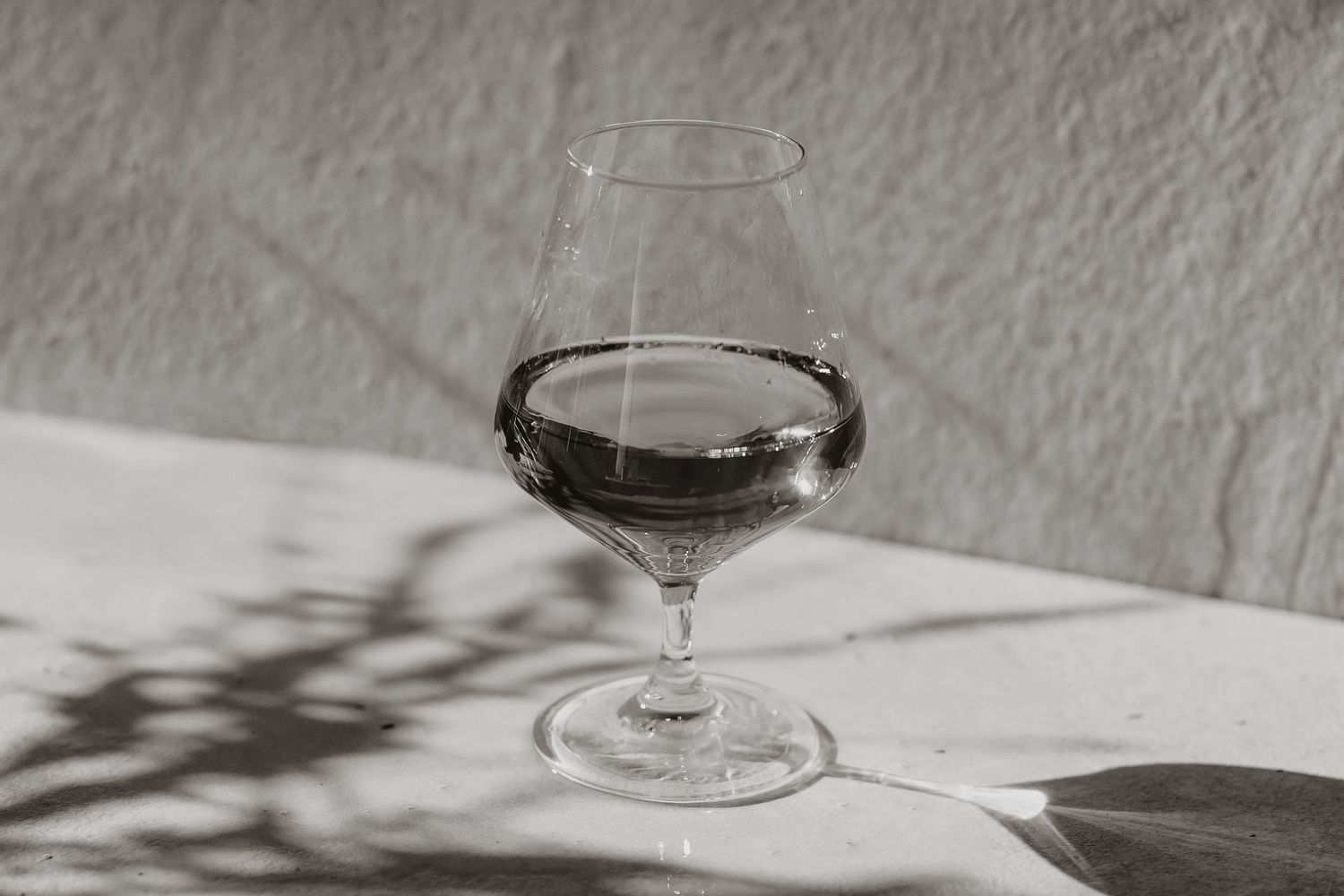 Vintage-style black and white photo of cocktail glass with dramatic shadow play.
