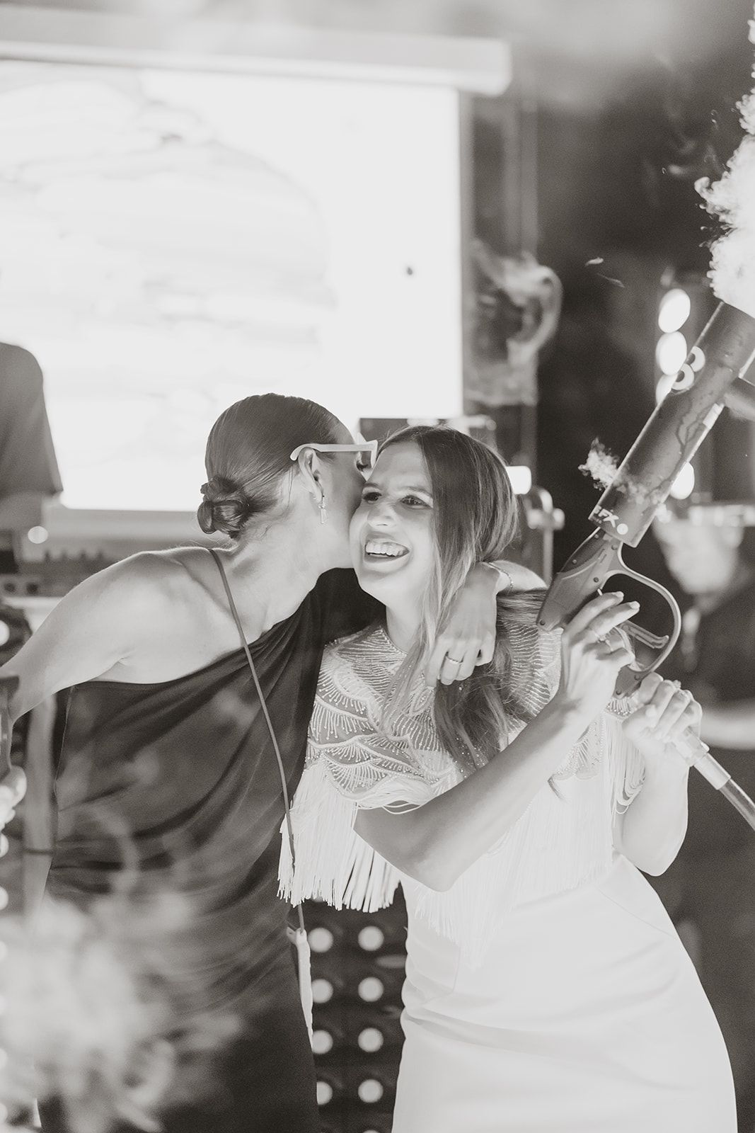Wedding party members celebrating with joyful expressions and raised arms on the dance floor.