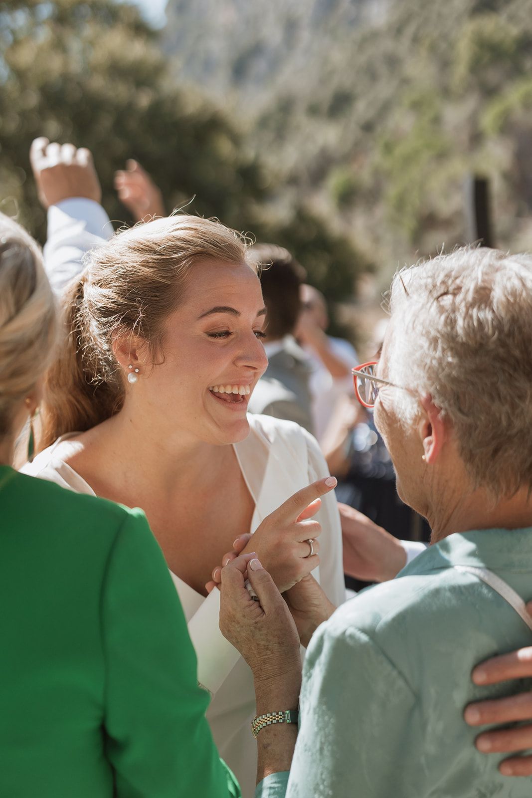 Guests share a joyful moment during an outdoor wedding celebration with mountains in the background.