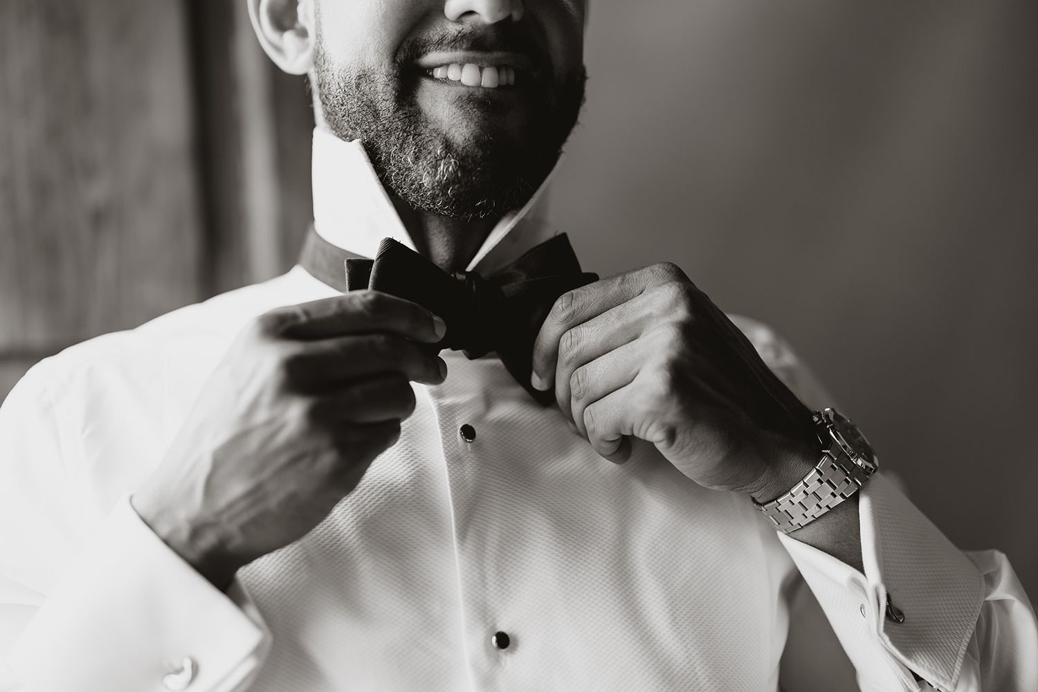 Black and white close-up of hands adjusting a formal black bow tie.