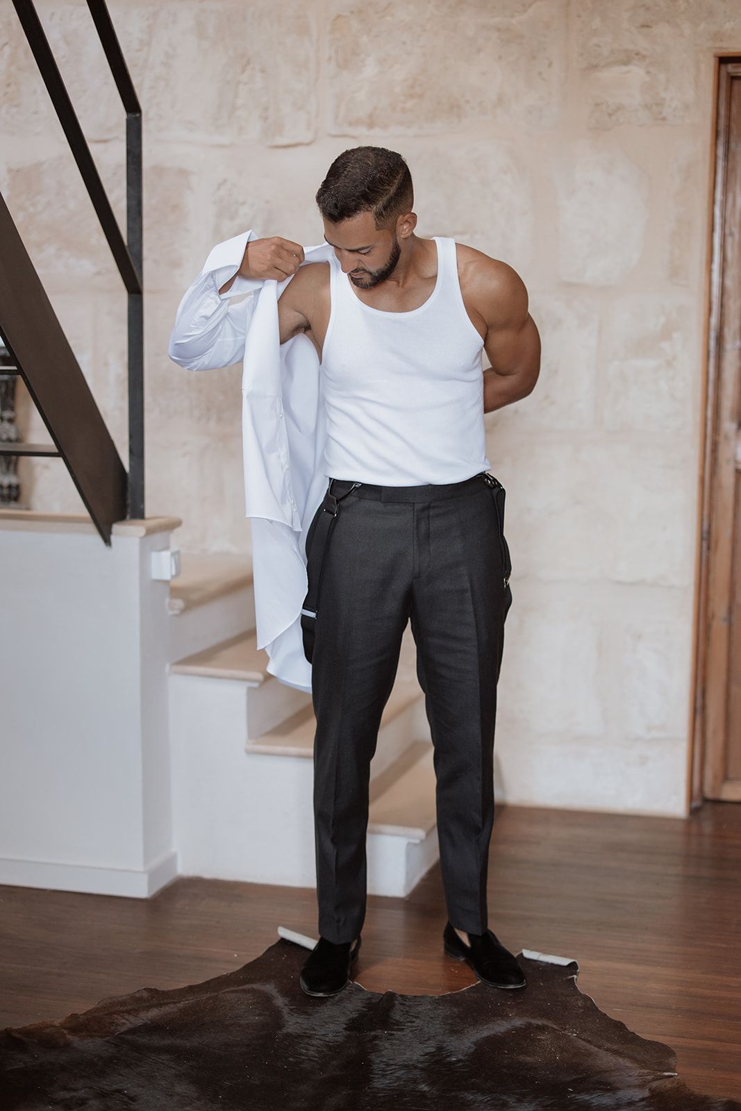 Person in white tank top and dark pants during formal dressing preparation.