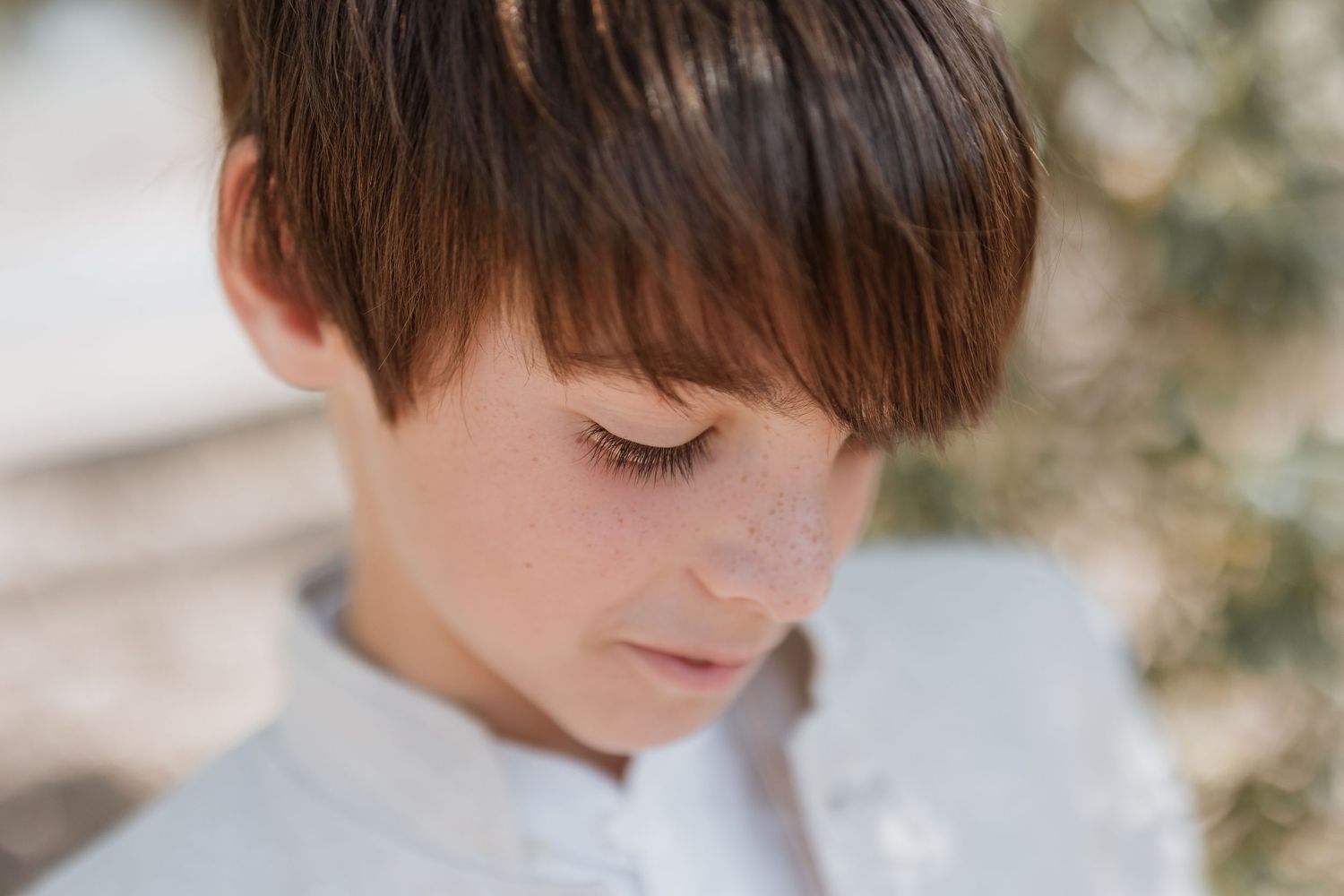 A young figure is captured in a quintet of softly-lit portraits with delicate features and brown hair.