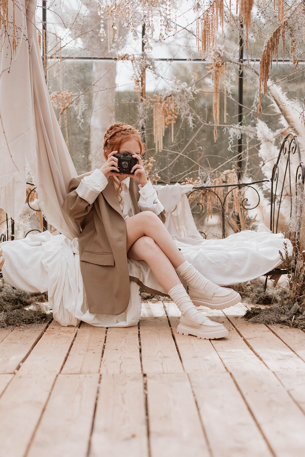 Vintage-style photography session in greenhouse with person holding camera on decorative swing.