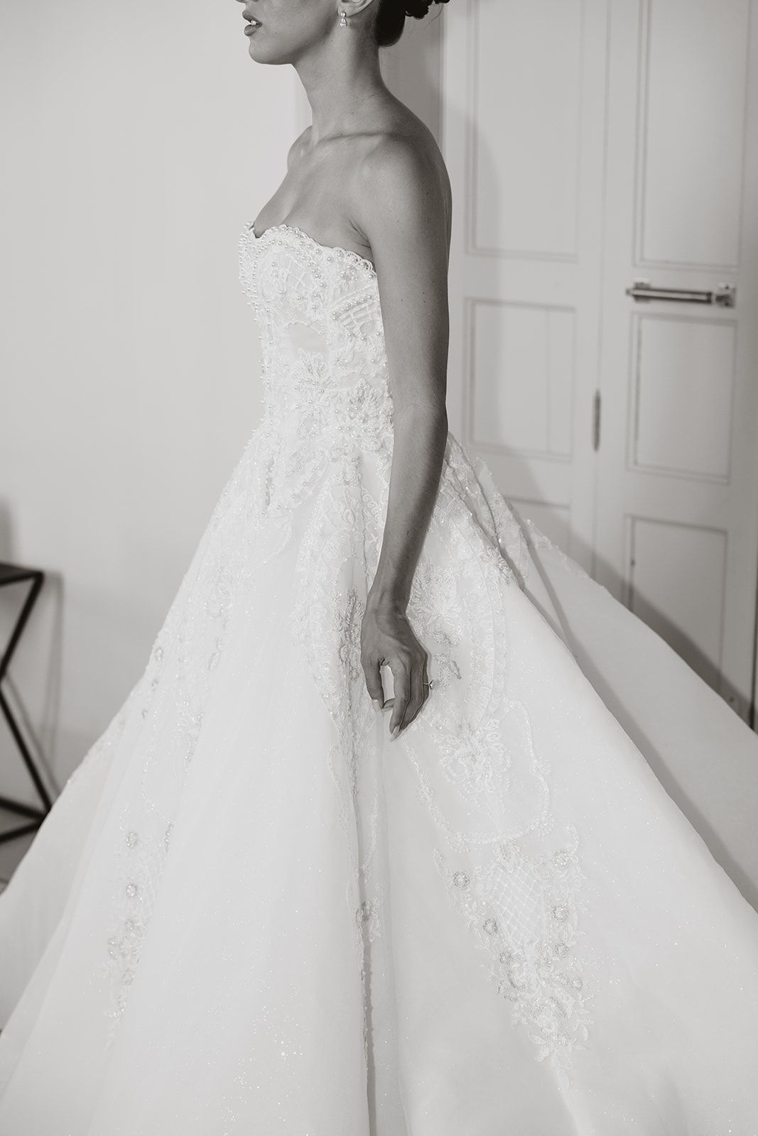 Side profile of elegant strapless wedding gown with detailed lace embellishments.