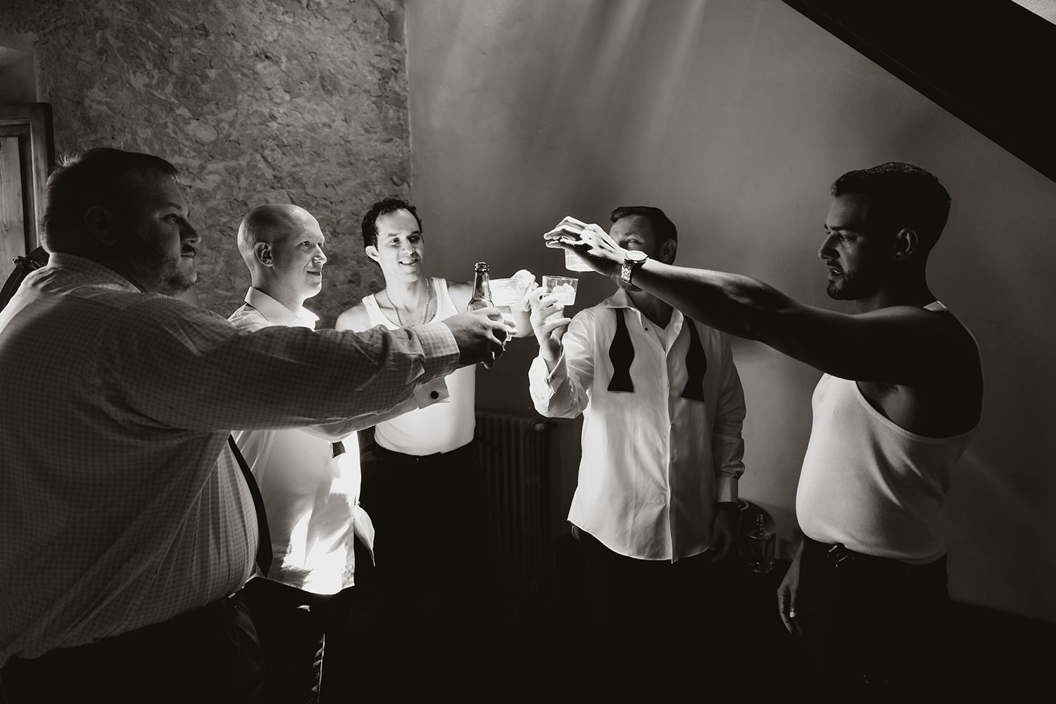 Black and white photo of group toasting with drinks during celebration.