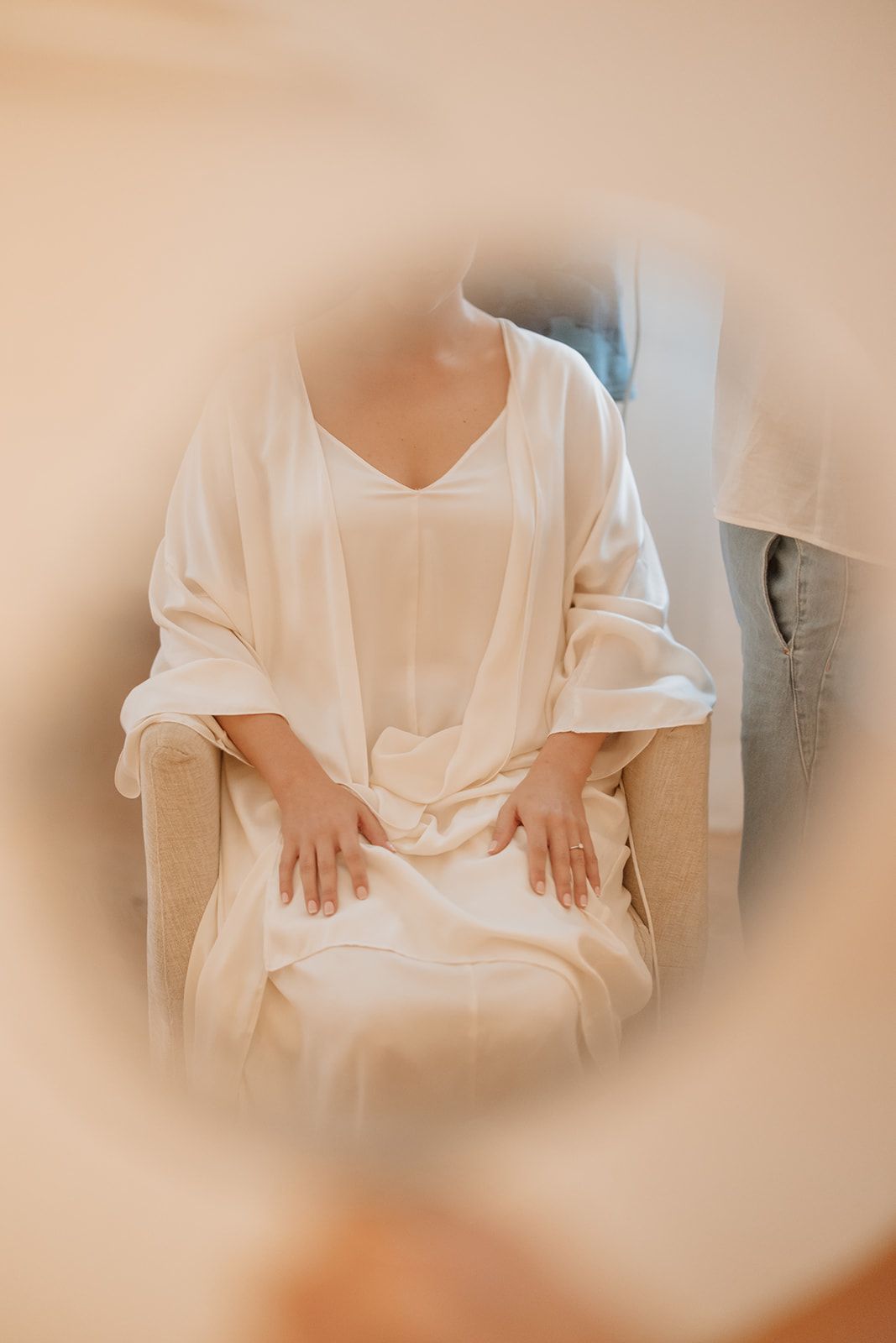 Person wearing flowing white robe sitting peacefully in soft ambient lighting.