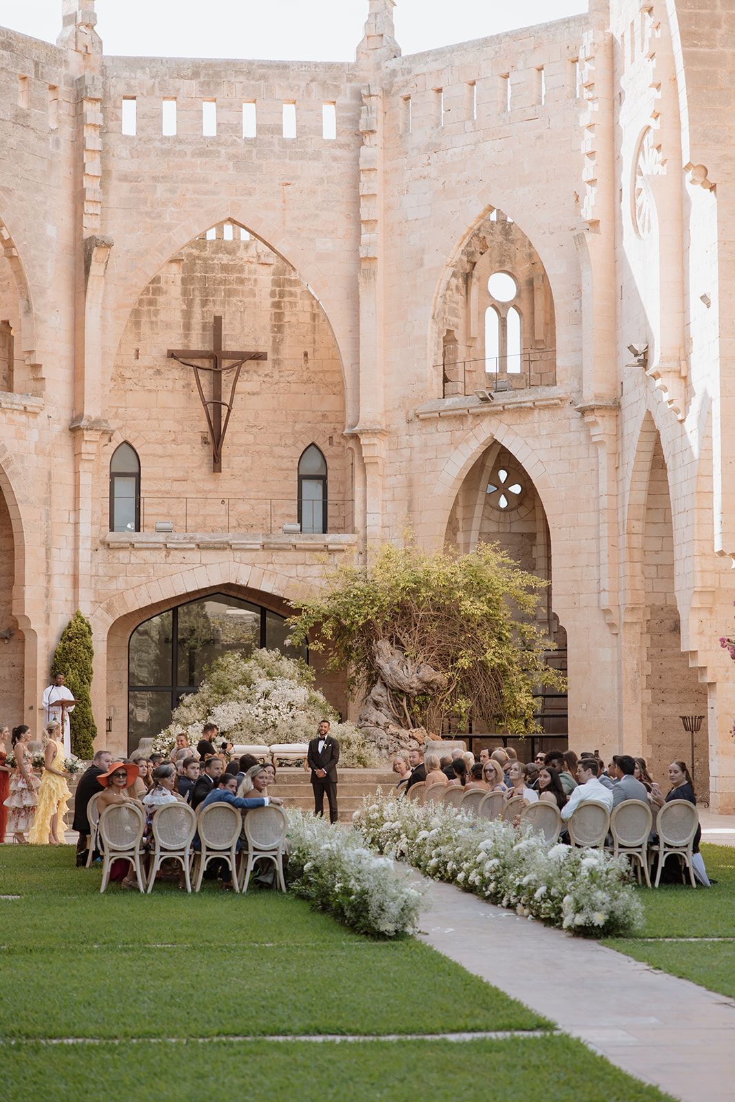Wedding ceremony setup with white chairs and floral aisle decorations inside historic church ruins.