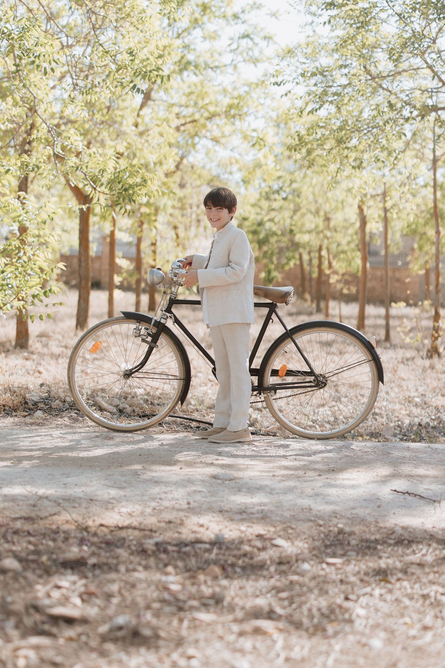 A vintage bicycle leans against a soft woven beige sweater on a sunlit trail through a wooded grove.