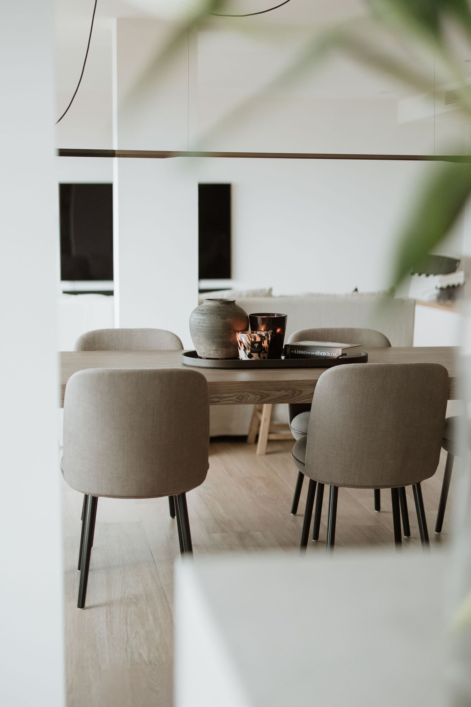 Modern dining area with gray upholstered chairs and dark table in minimal white interior setting.