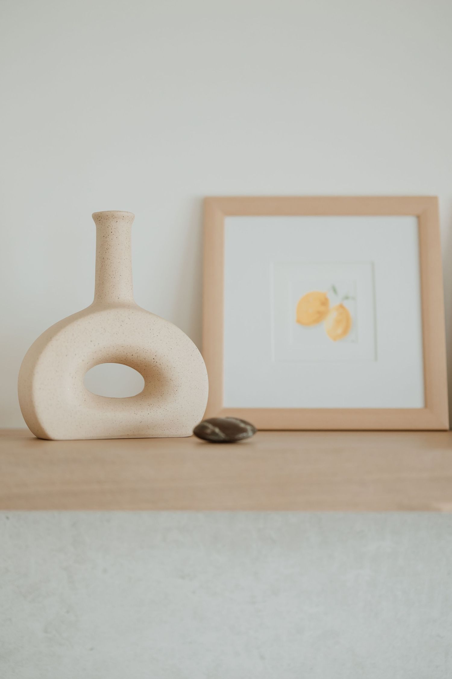 Modern shelf display featuring a sculptural vase and framed citrus artwork.