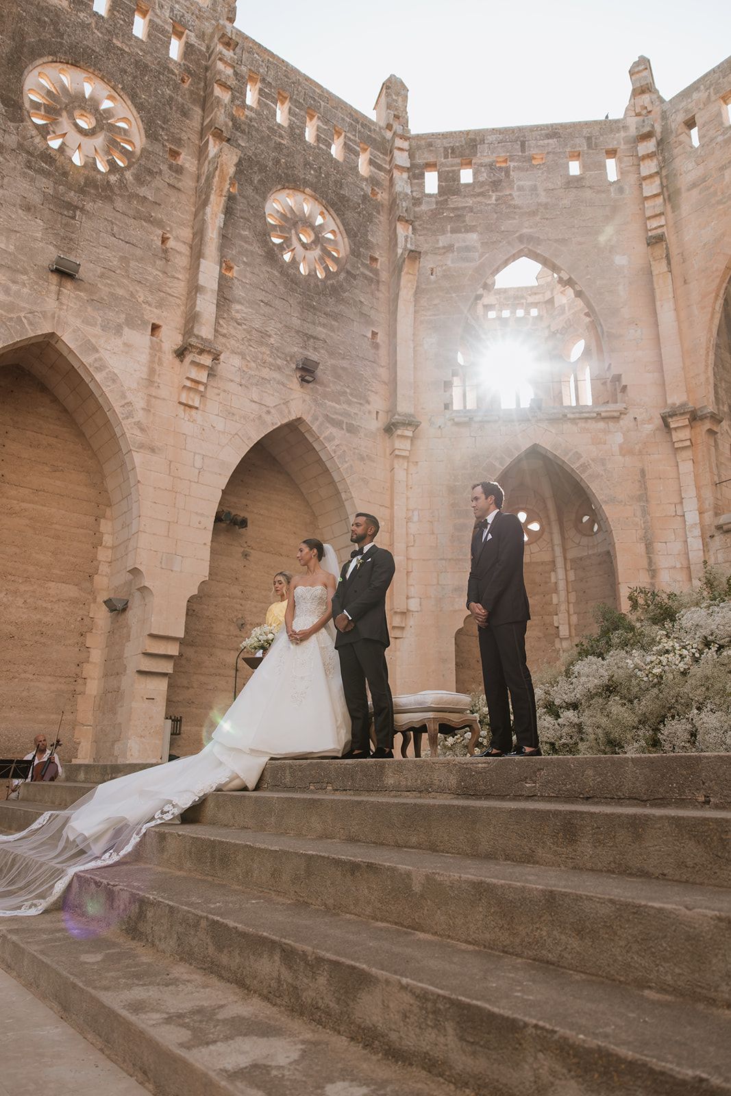 Wedding ceremony taking place on stone steps inside a historic cathedral with dramatic arched architecture.