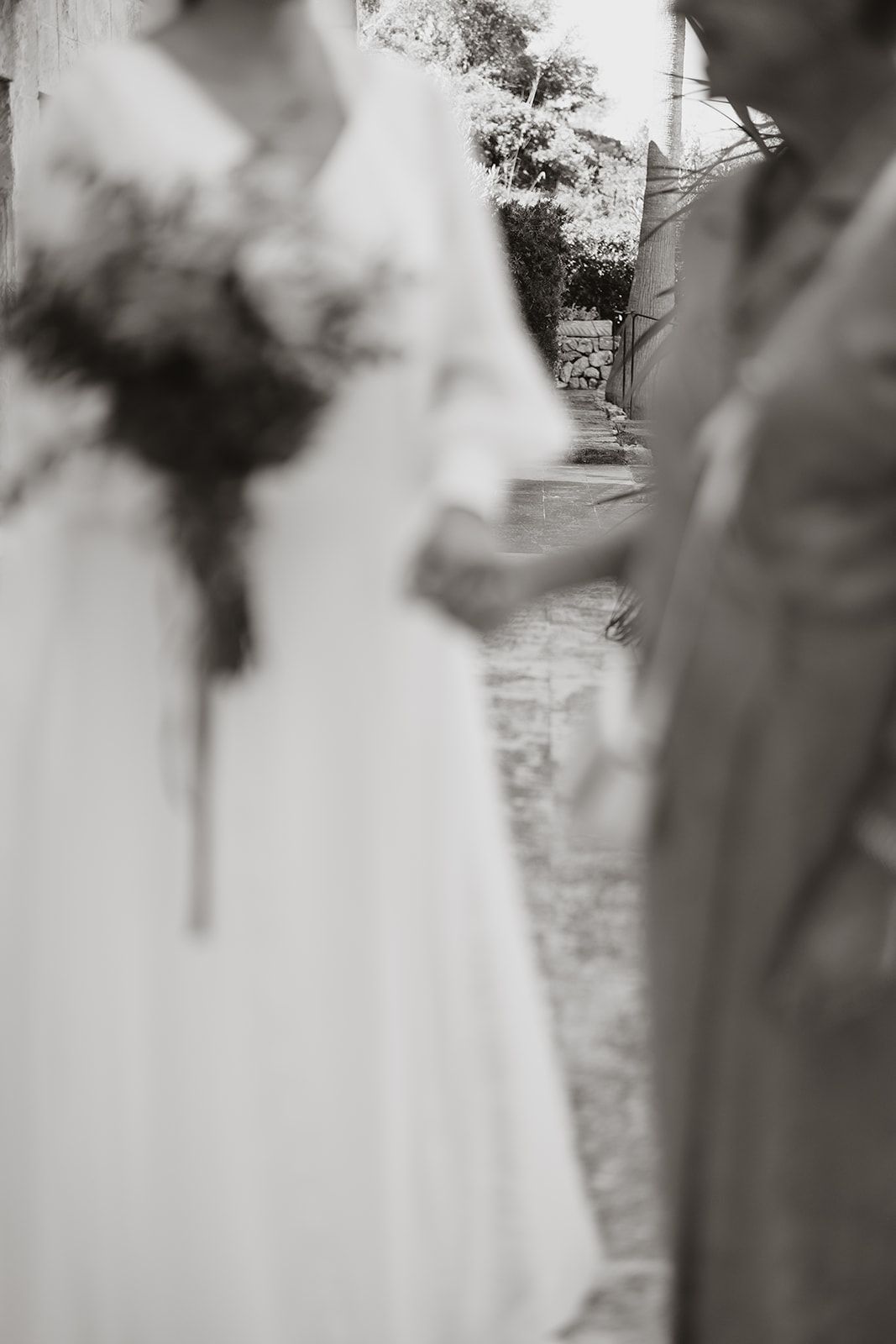 Artistic black and white photo showing blurred wedding details and bouquet.