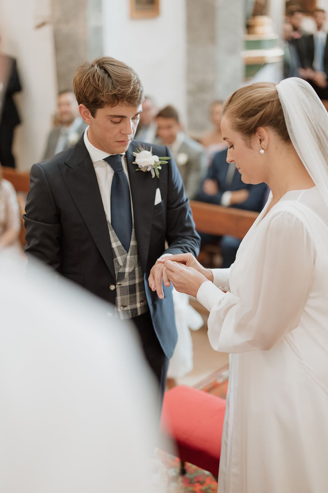 Wedding ceremony at a church with couple exchanging rings on red carpet.