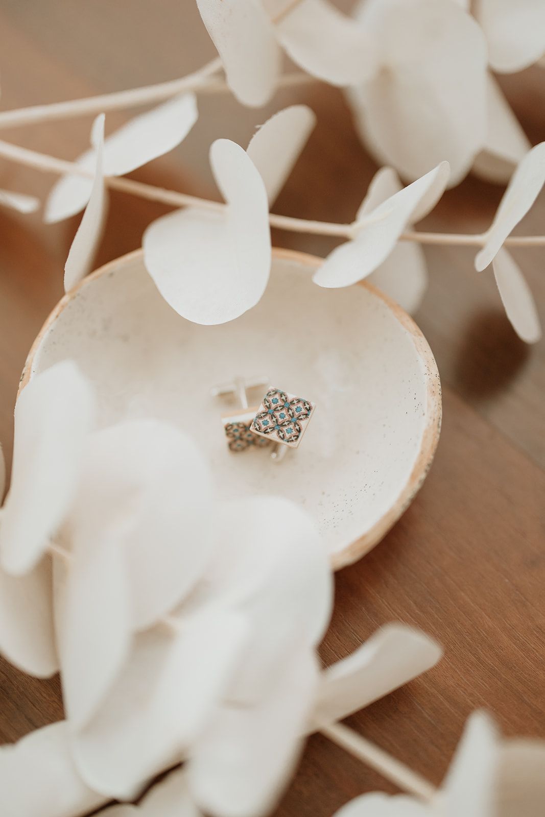 Delicate engagement ring nestled in a white ceramic dish surrounded by paper butterflies.