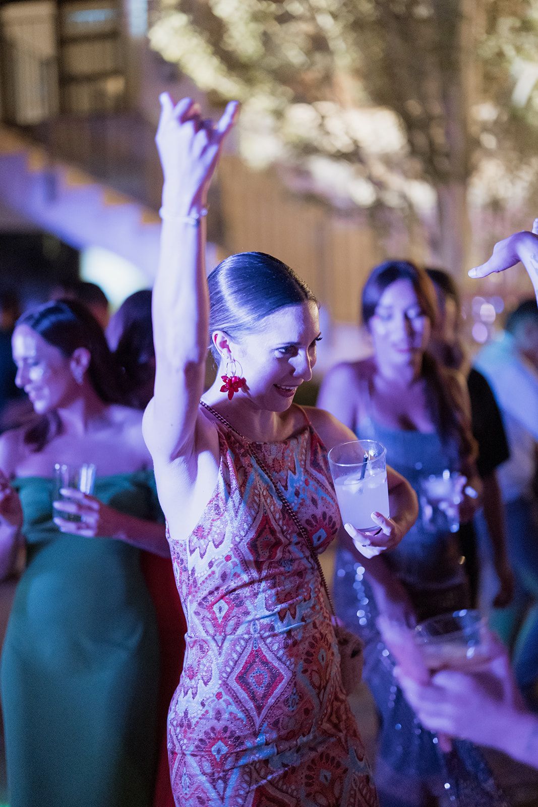 Guests dancing under purple lighting at an evening outdoor celebration.