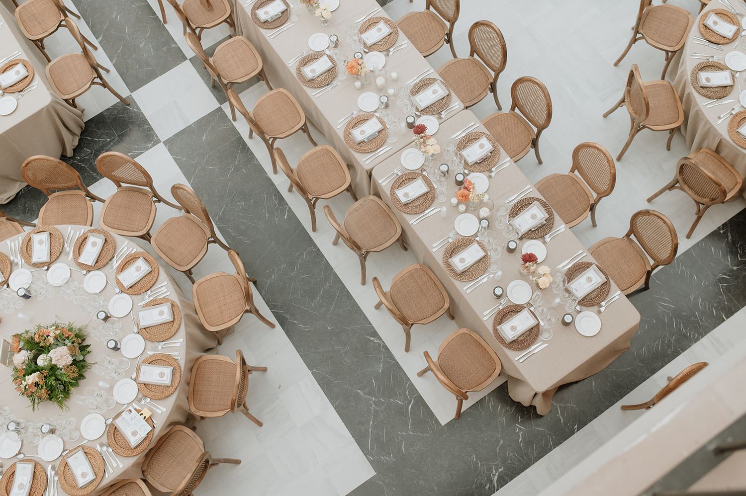 Aerial view of wedding reception tables arranged with tan chairs and white linens.