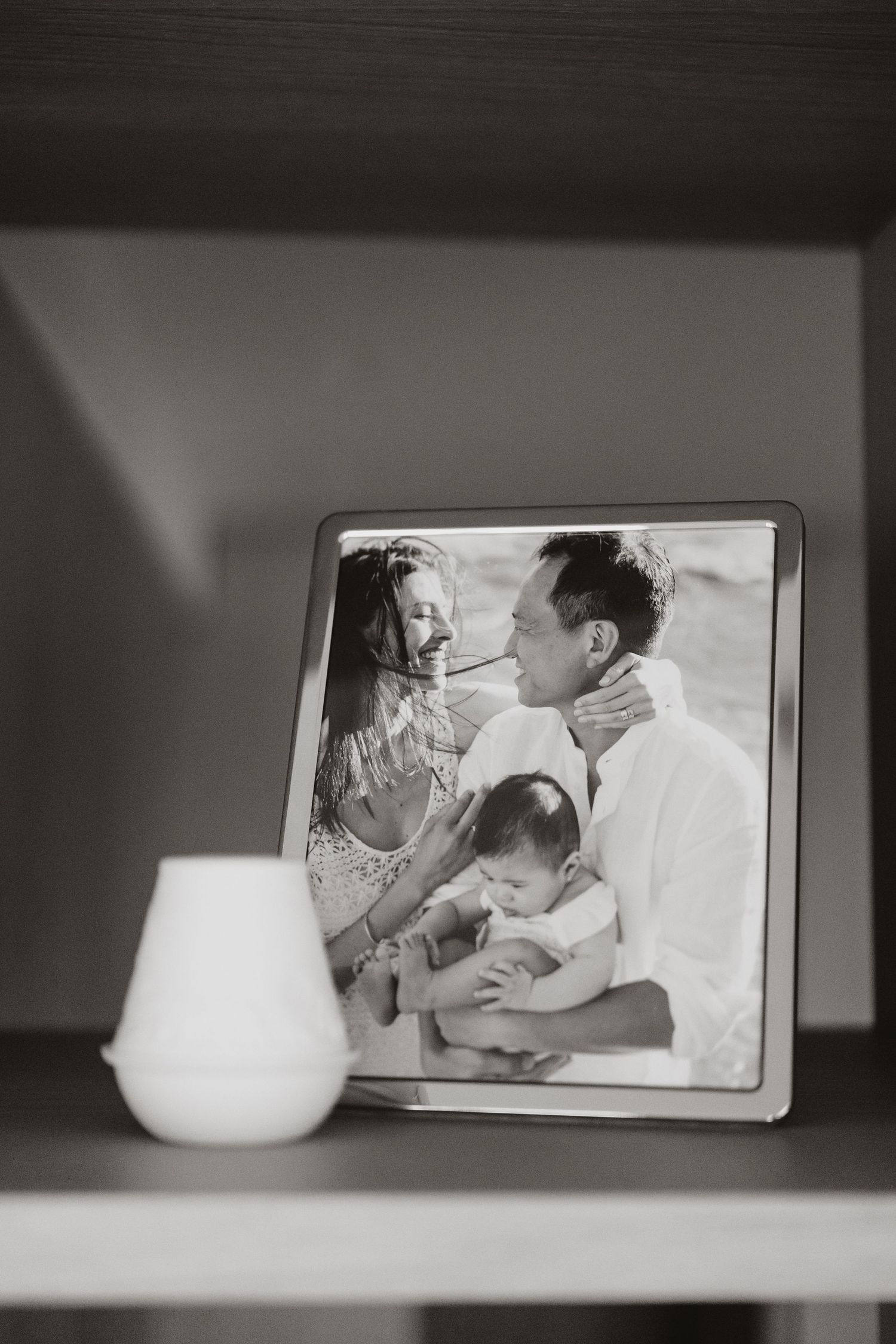 Black and white photographs displayed on shelf with white ceramic vase.