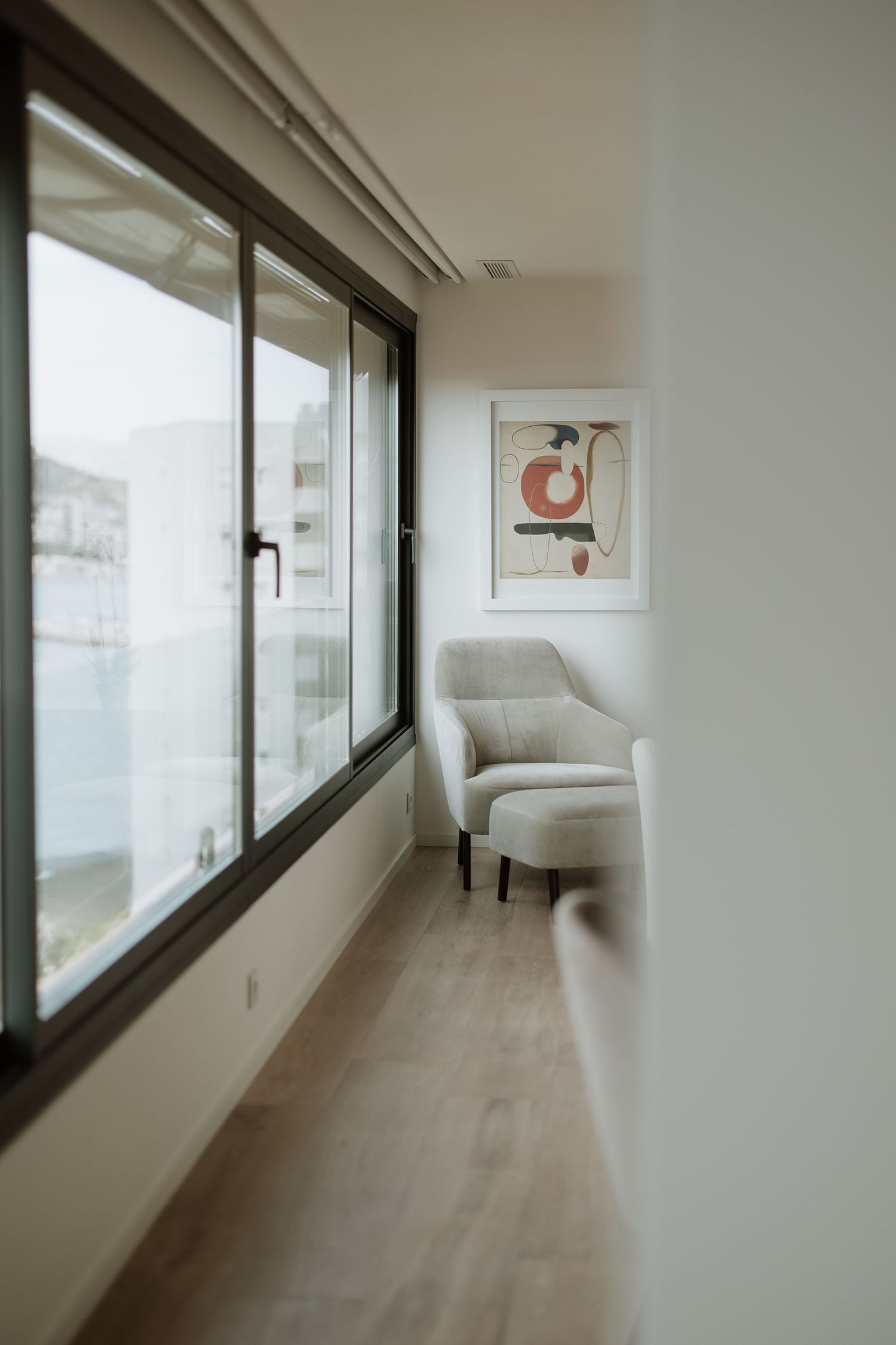 Modern interior space with a white armchair and large window overlooking a city view.