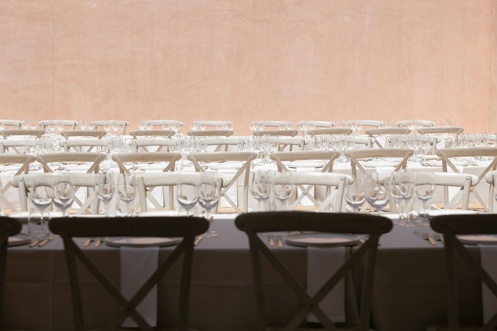 Close-up of ornate white chairs arranged at wedding reception tables.