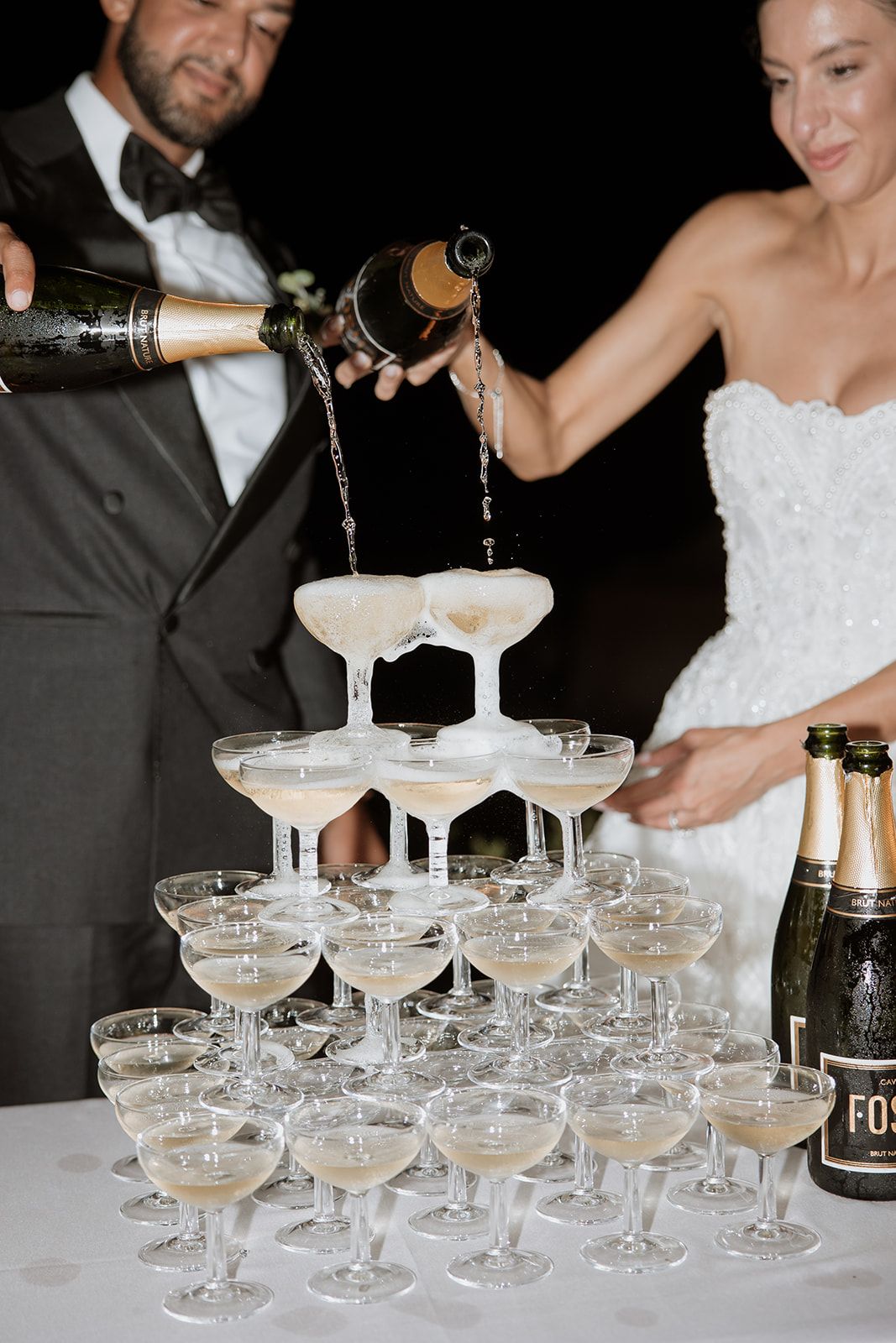Celebratory champagne tower being filled during an elegant wedding reception.