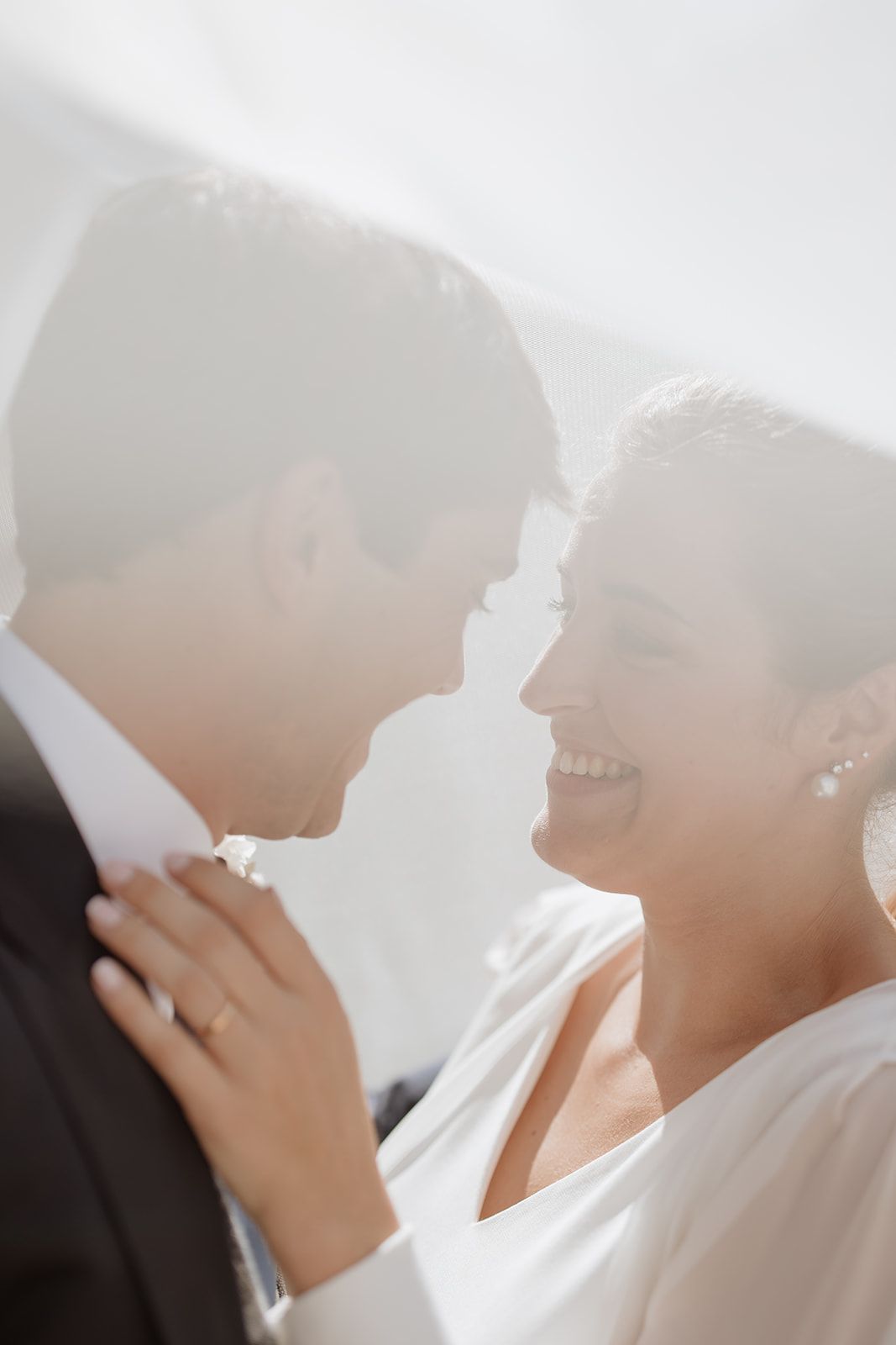 Intimate wedding portrait of newlyweds sharing a tender moment in soft sunlight.