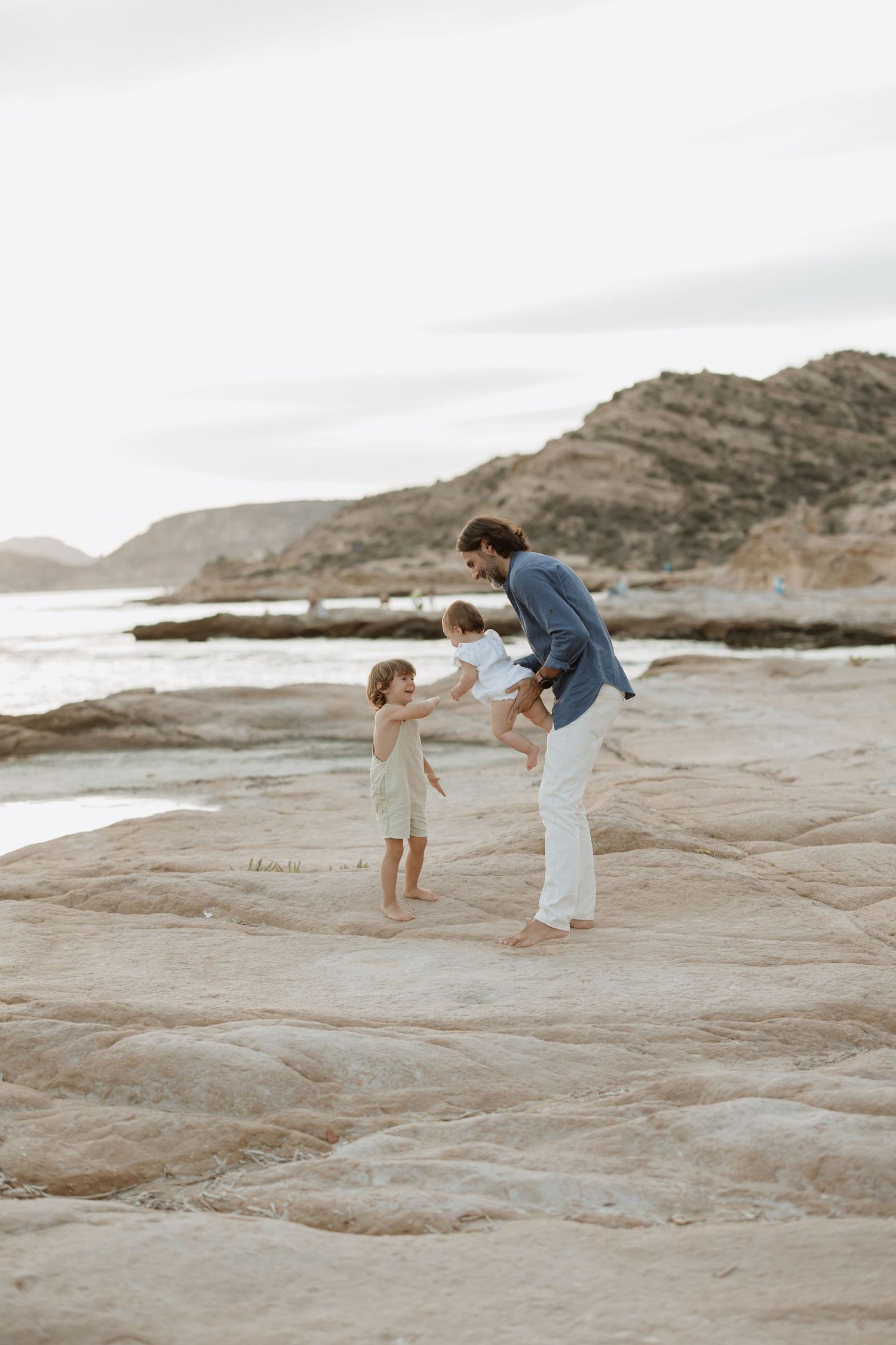 Playful moment on rocky coastal landscape during sunset.