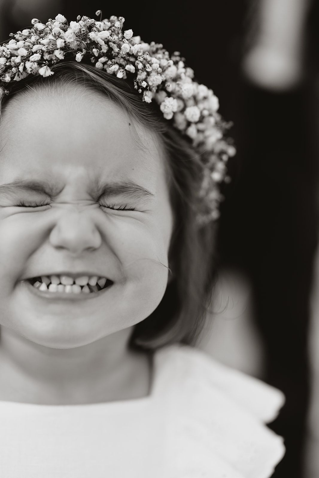 Black and white portrait of joyful expression with floral crown.