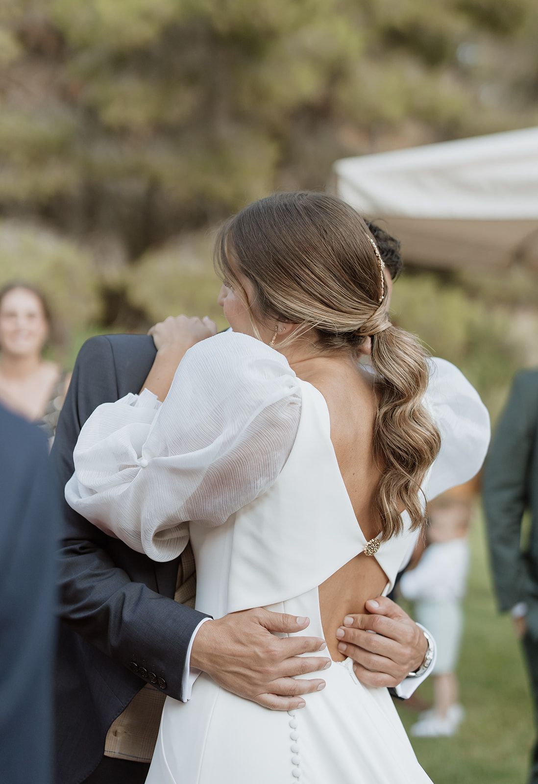 An intimate embrace captured during an outdoor wedding celebration.