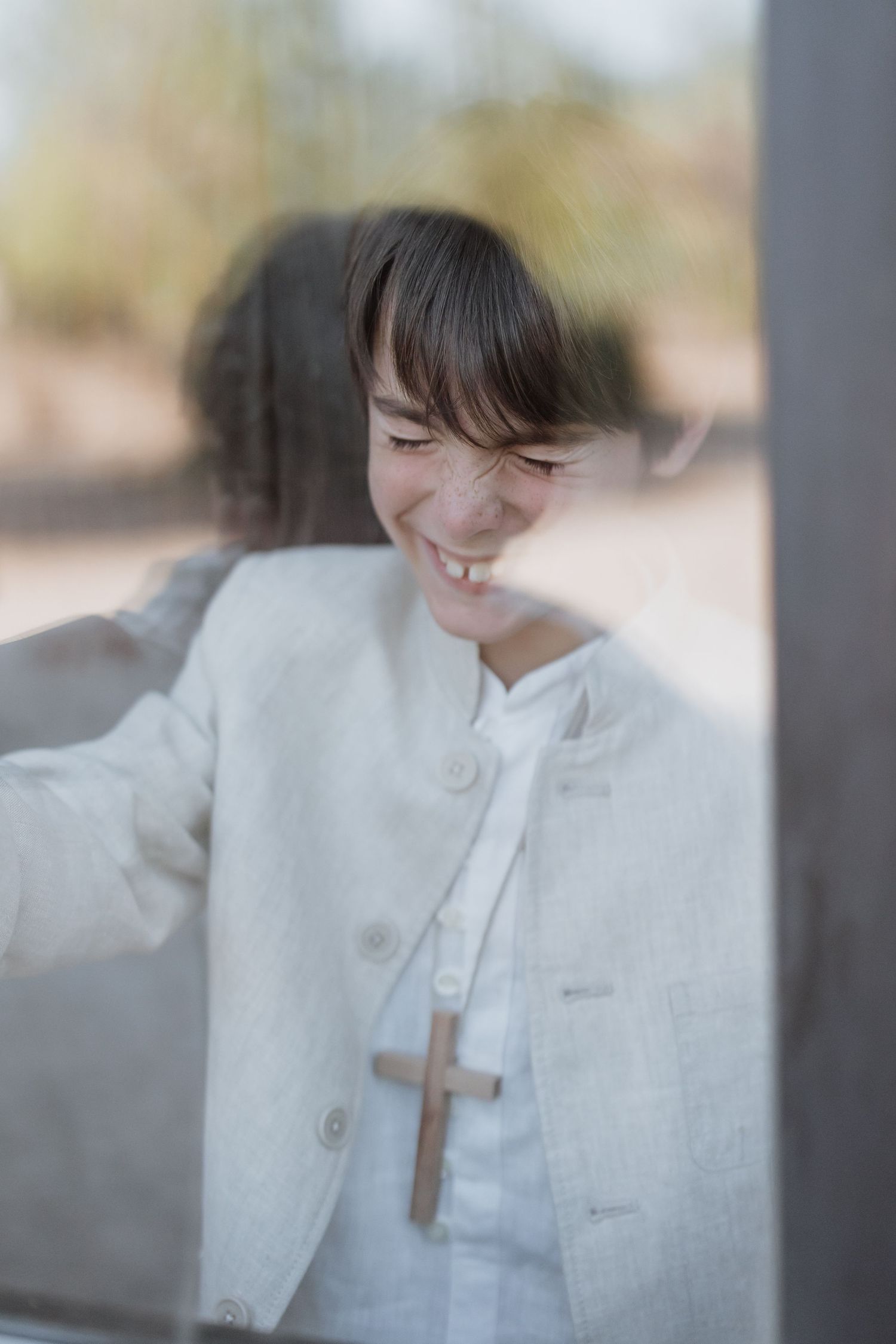 A person in a white button-up jacket smiles joyfully while looking down, captured through a soft-focus dreamy lens effect.