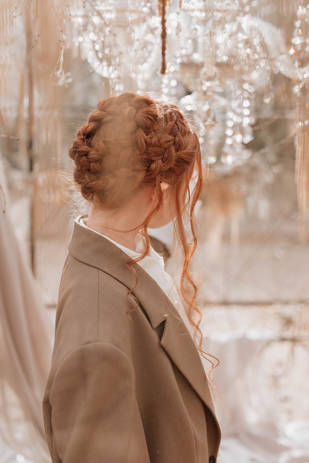 Side profile portrait showing intricate braided hairstyle and tan blazer in greenhouse setting.